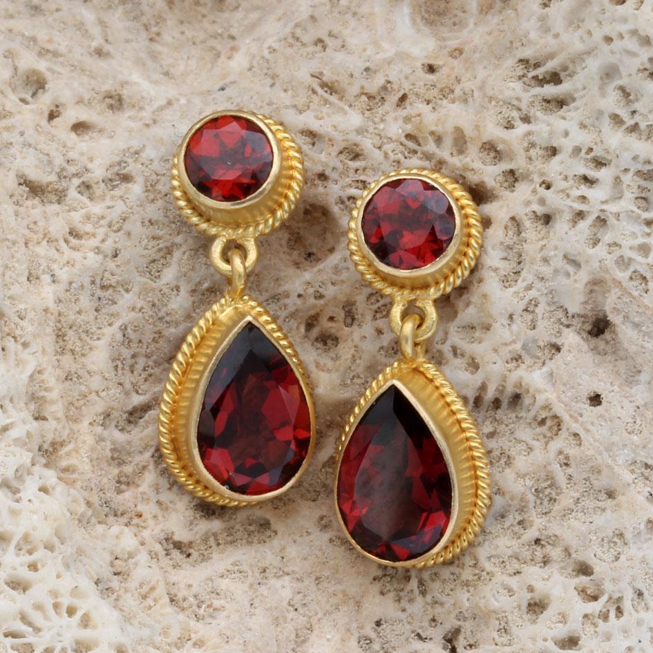 Bright red 7 x 9 mm pear shaped faceted garnets that are set in matte-finish 18K bezels and bordered by delicate twist wire accents dangle below 5 mm faceted rounds in similar settings in these classically simple artisan crafted post earrings. A