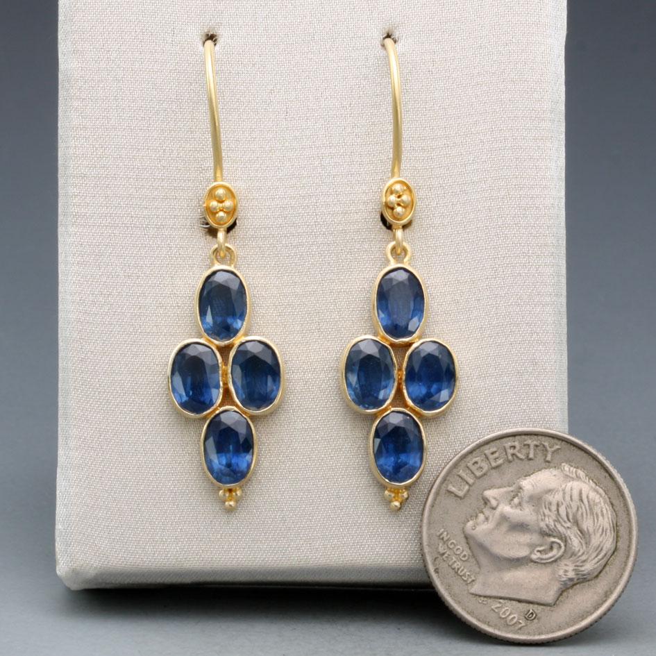 Four lively 4 x 6 mm faceted blue sapphires are arranged in a vertical alignment with small 