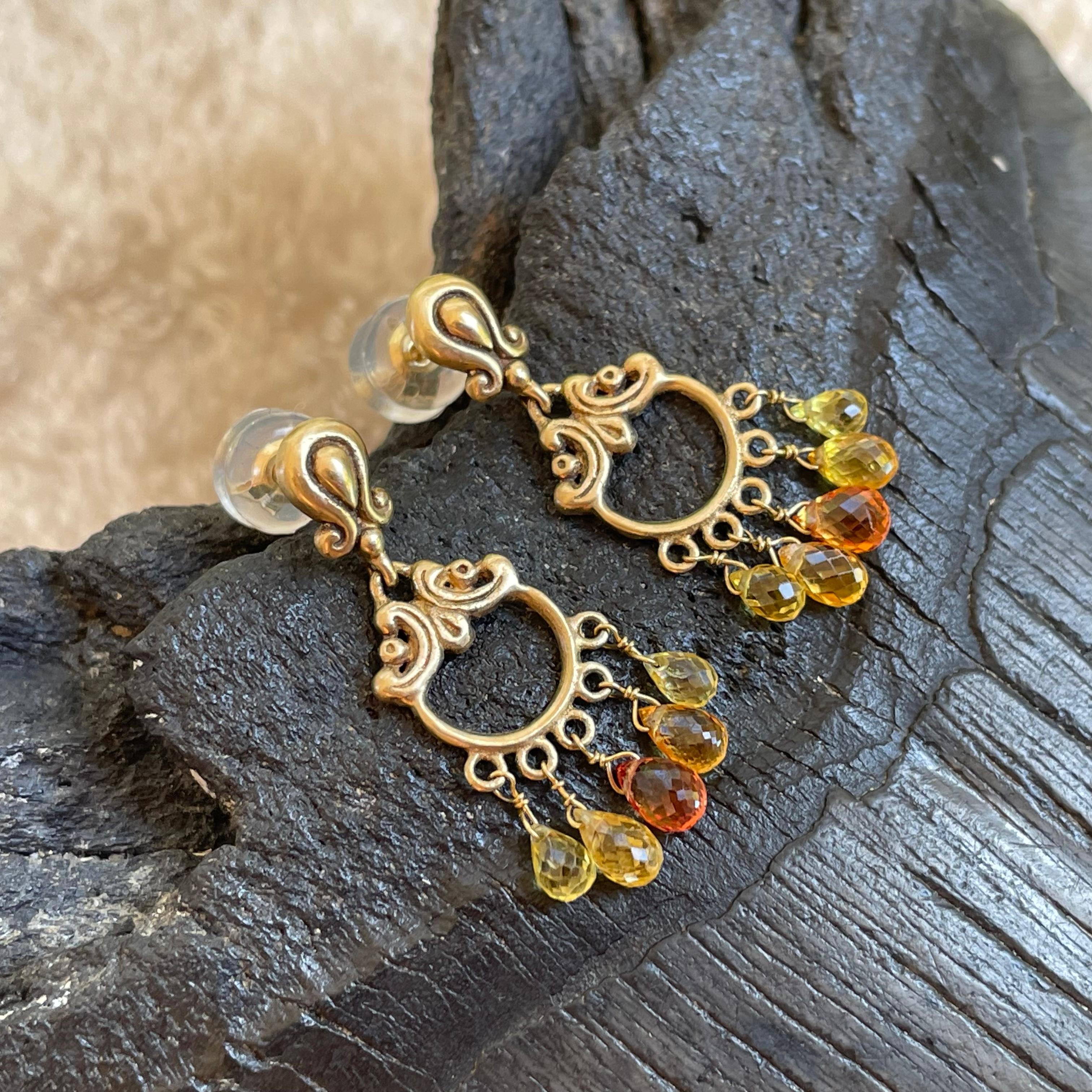 Diez gotas briolette de zafiro facetado de 3 x 5 a 4 x 6 mm de color amarillo a naranja cuelgan bajo aros de 18 quilates tallados en cera a juego y espigas esculpidas decoradas en espiral en este elegante diseño de pendientes.  Cómodas tuercas de