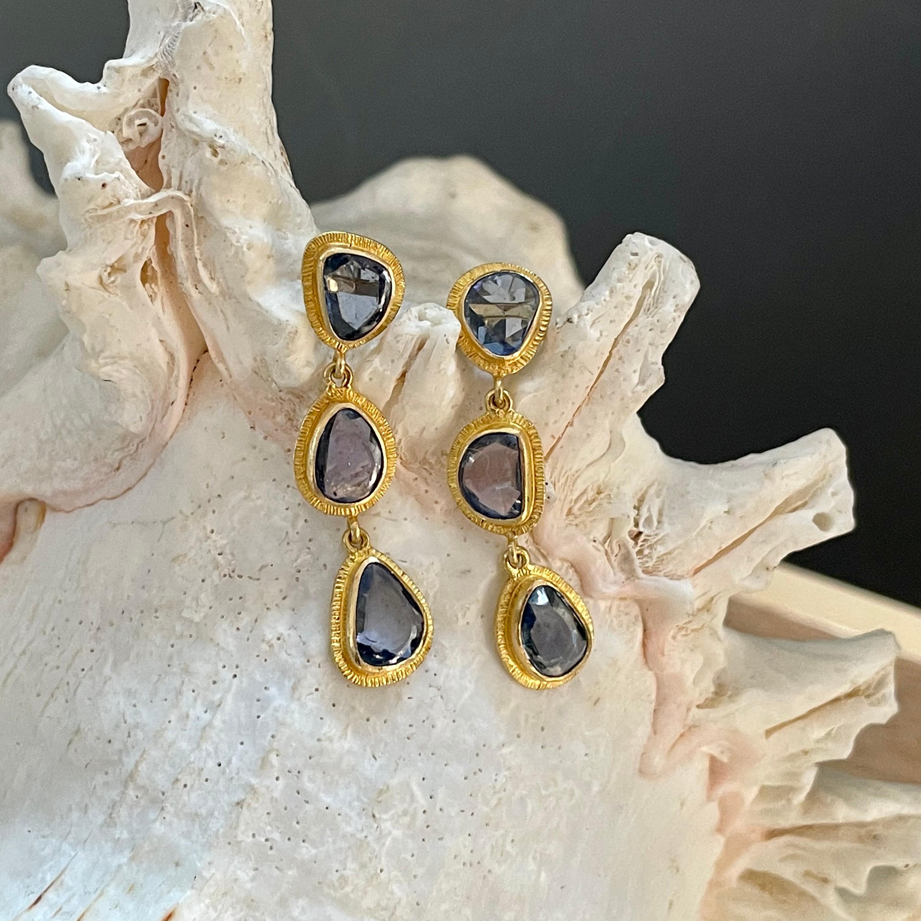 Six slightly irregular shaped buff-top lively blue sapphires between 5 x 6 to 6 x 8 mm set in organic line texture bezels cascade down in this Steven Battelle post earring creation.  Delightful. 
