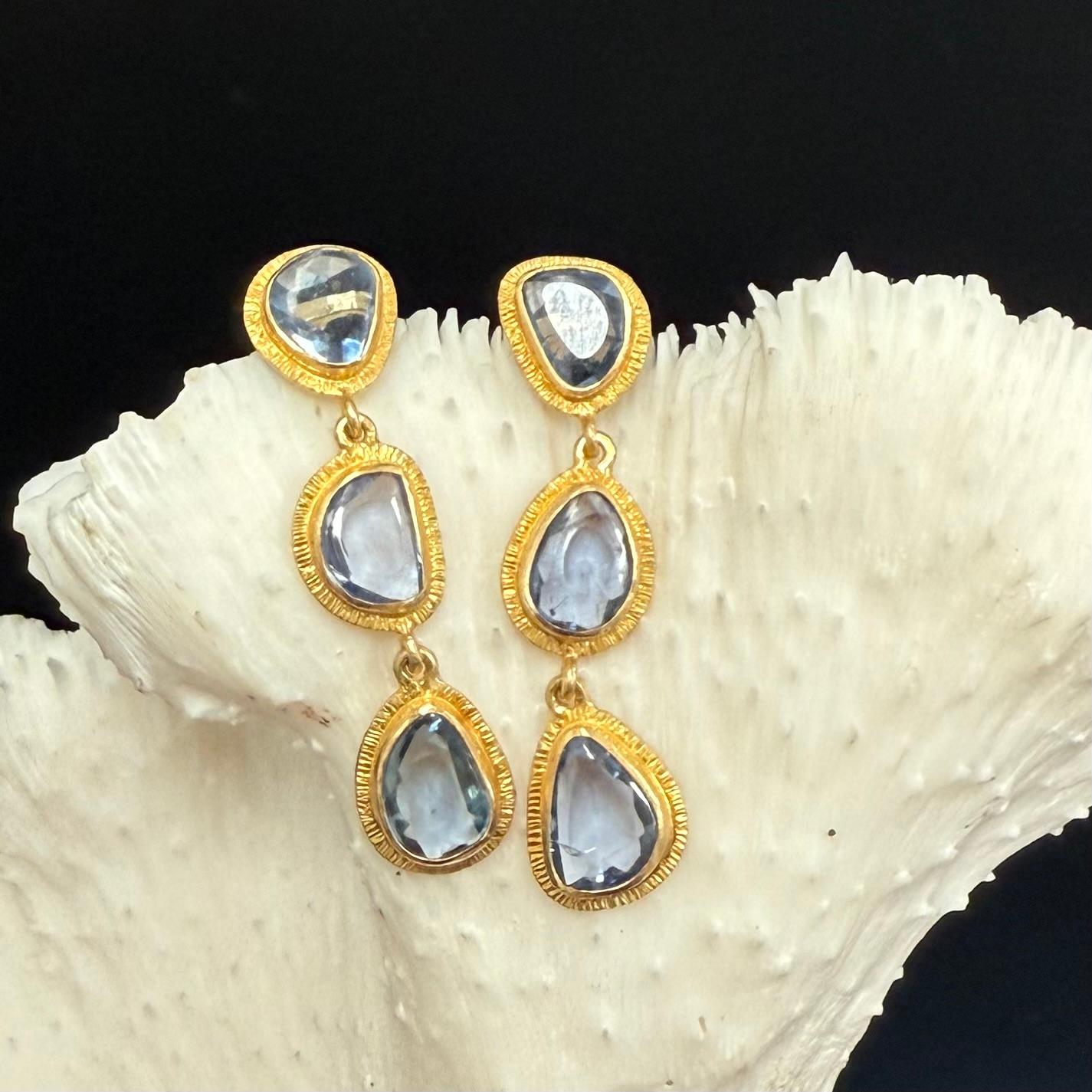 Six slightly irregular shaped buff-top lively blue sapphires between 5 x 6 to 6 x 8 mm set in organic line texture bezels cascade down in this Steven Battelle post earring creation.  Delightful. 
