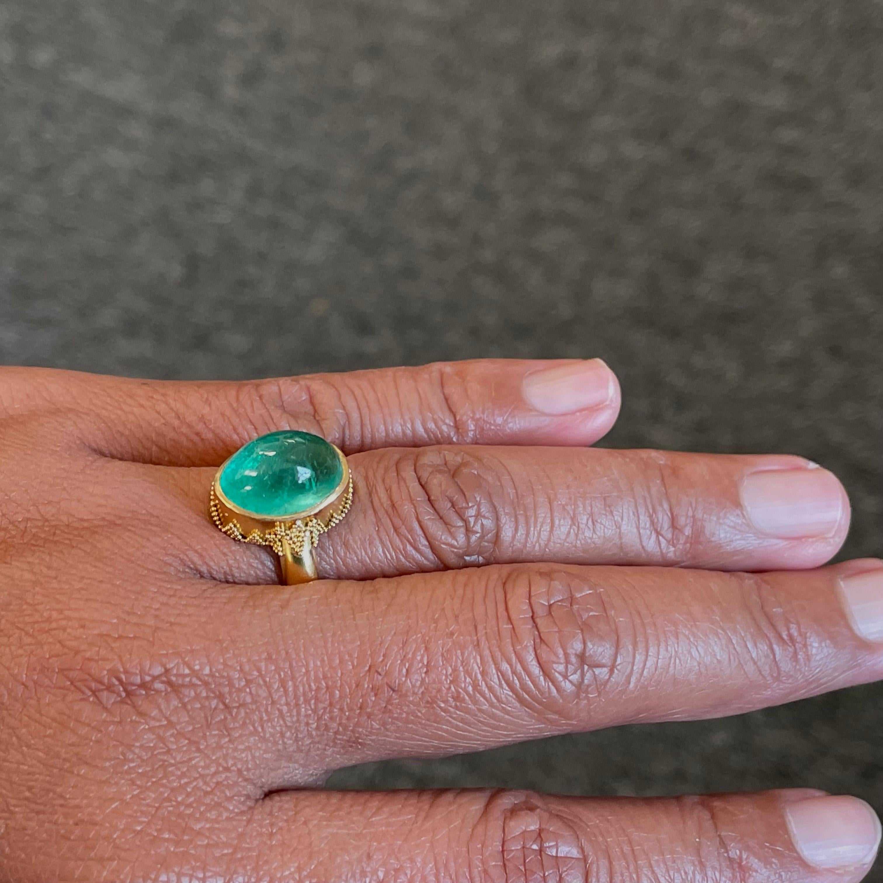 A beautiful, clear, light green Columbian 9 x 13 mm emerald cabochon is set in classic geometric granulation on a substantial matte finish band currently sized 7 in this handmade masterpiece.
A treasure for a lifetime.  This ring is resizable.