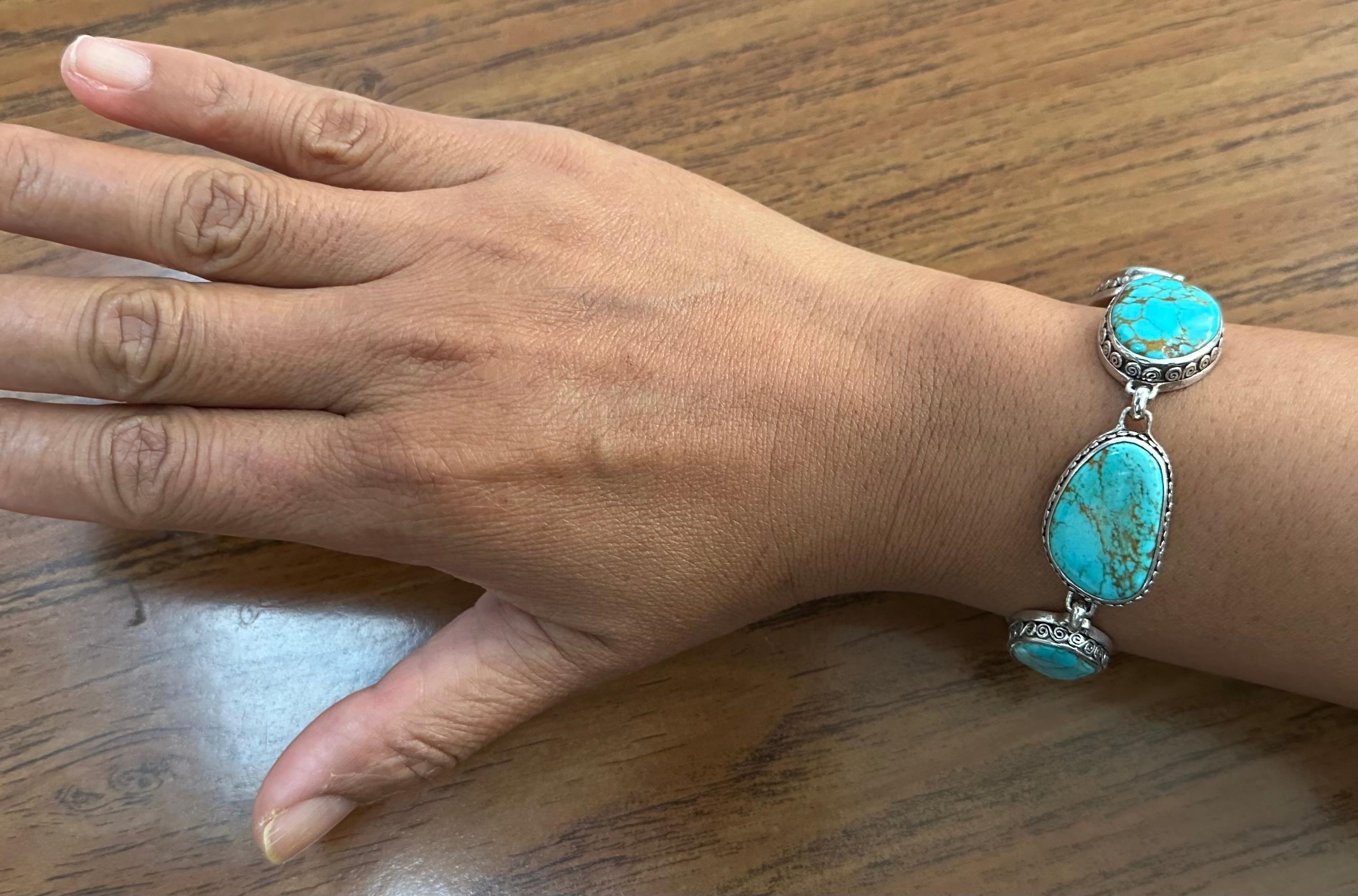 Six irregular shaped, approximately 14 x 22 mm cabochons of Arizona Kingman mine turquoise are set in sterling silver bezels each decorated with a unique slightly different spiral motif to create this one of kind turquoise bracelet.  The golden