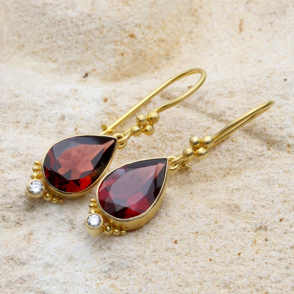 Two brilliant red 8 x 12 mm pear shaped faceted garnets are held  in artisan crafted 18K gold bezels with 2.2 mm VS1 diamond accents sparking below along with delicate 