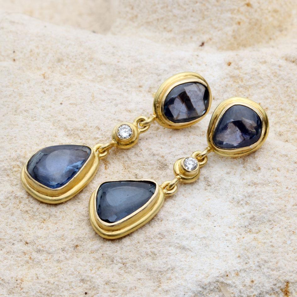 Slightly irregular 7 x 9 mm buff-top blue sapphires are surrounded by round 18K wire borders and dangle below central 2 mm VS1 faceted diamonds, all beneath the slightly smaller upper sapphire posts..  A lovely artisan crafted organic look that