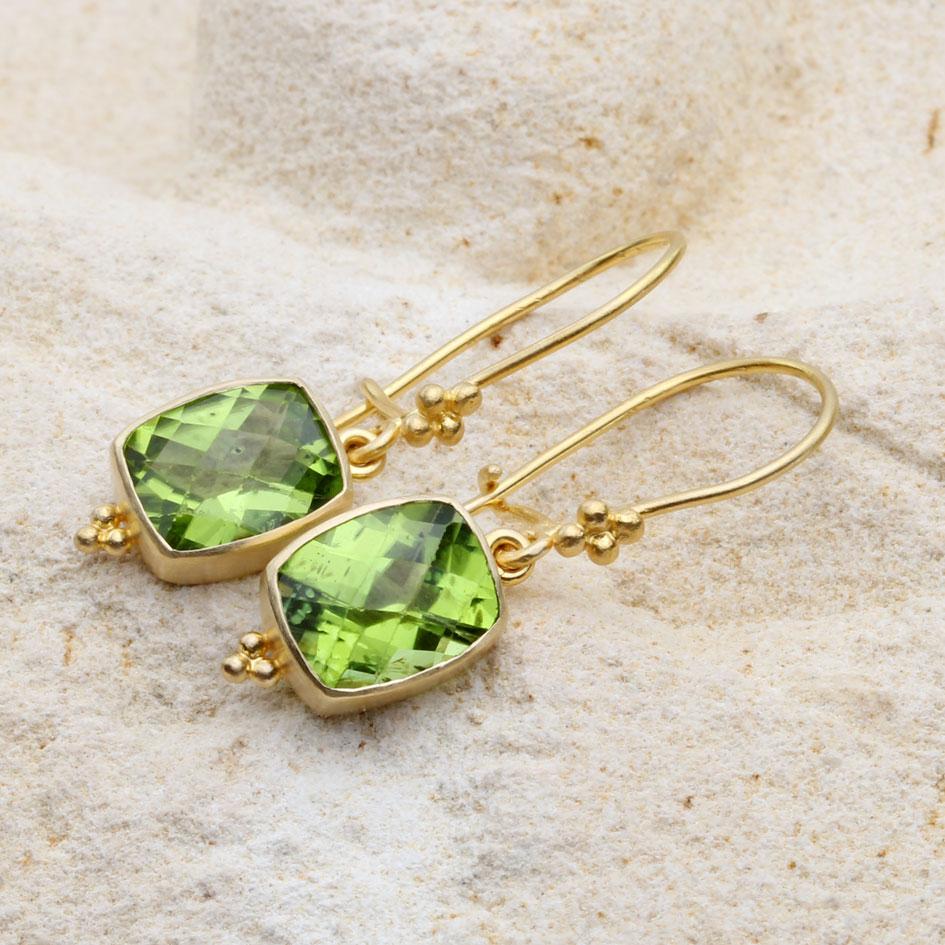 Two lively and bright 8 x 10 mm cushion shaped checkerboard faceted peridots are set in artisan crafted matte-finish 18K gold bezels decorated with 3 handset 