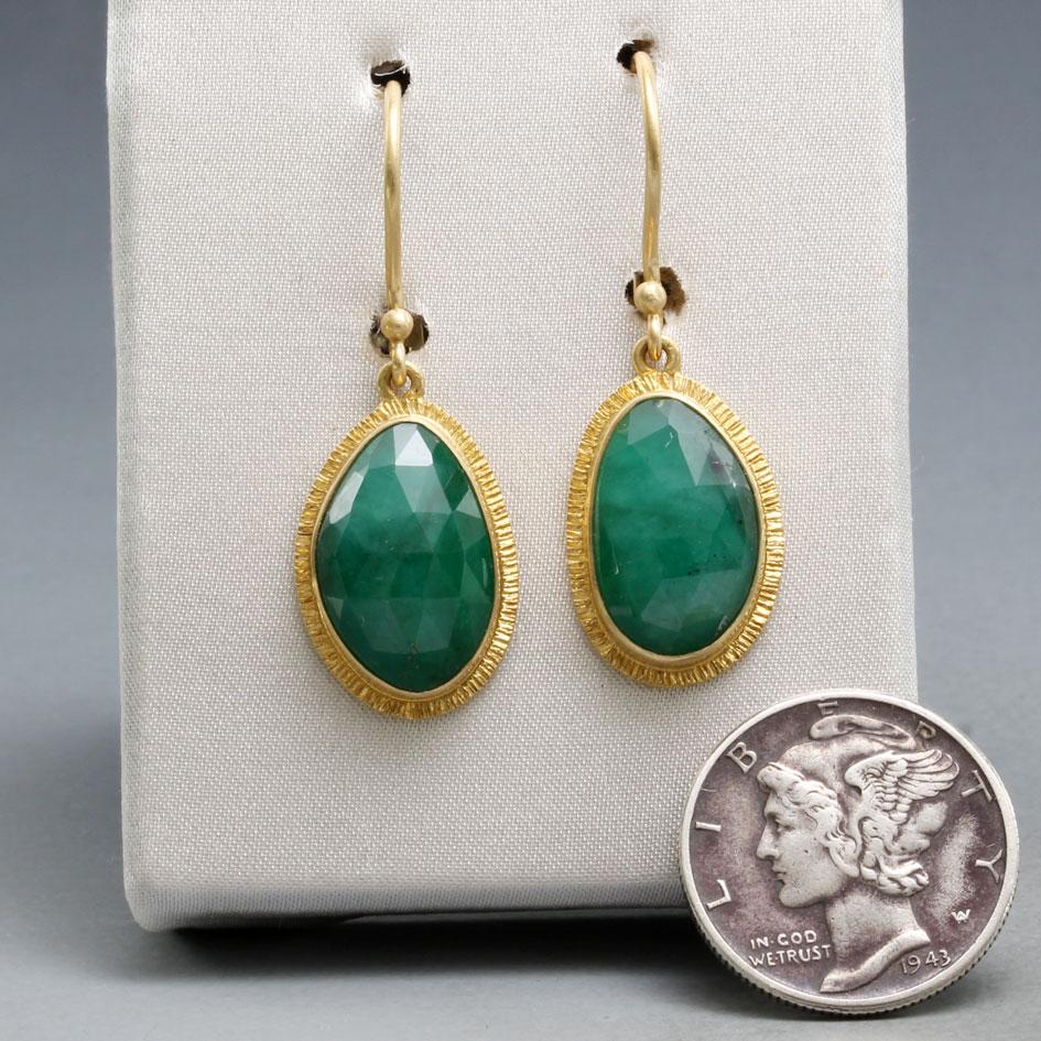 Two deep green approximately  8 x 13 mm semi-oval rose cut Zambian emeralds rest in matte-finish organic line textured 18K gold bezels below 18K safety clasp wires in this attractive design. A very substantial amount of emerald for a really