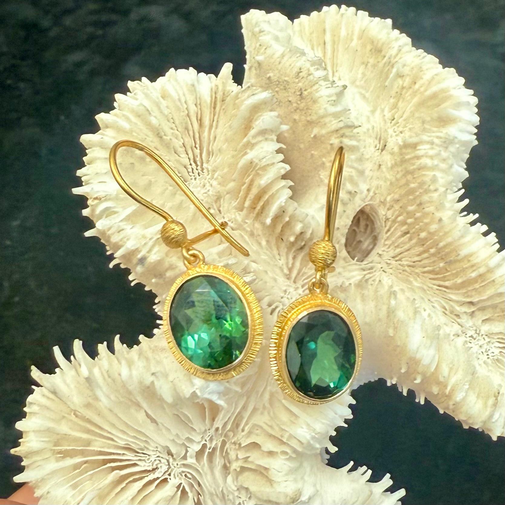 Due tormaline verdi ovali sfaccettate di 9 x 11 mm creano un meraviglioso contrasto tra il verde intenso e l'oro in questi orecchini con fili di sicurezza.  Tutte incastonate in una ricca finitura opaca in oro 18 carati, le pietre sono circondate da