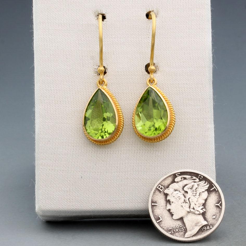 Grandi peridoti sfaccettati a forma di pera di 8 x 12 mm sono circondati da delicati accenti 