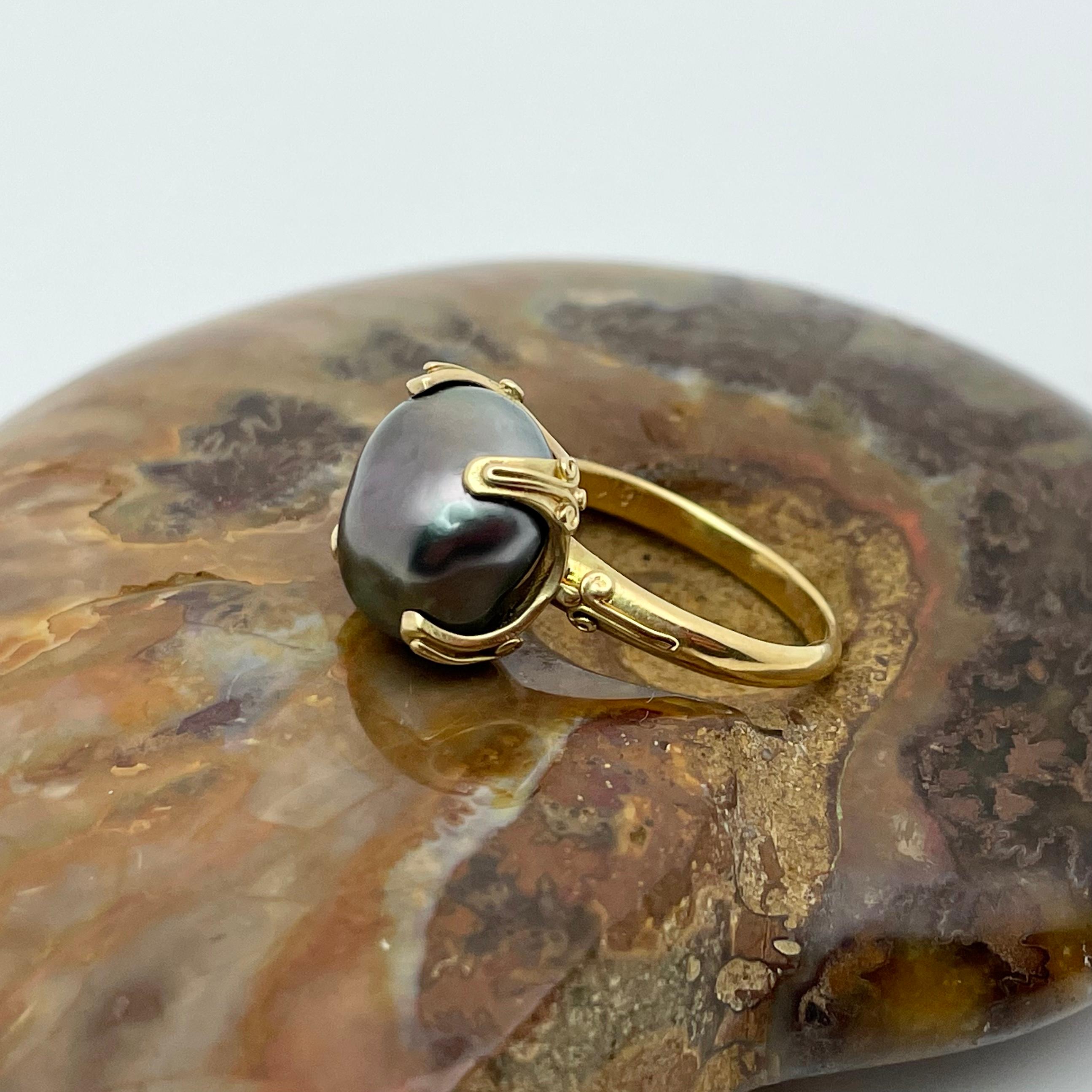 A lustrous slightly irregular shaped black south sea pearl is held in a handmade 4 corner embrace with small wire accents applied on the bezel and shank.  This ring is currently sized 6.5.  It is resizable. Delightfully unique!