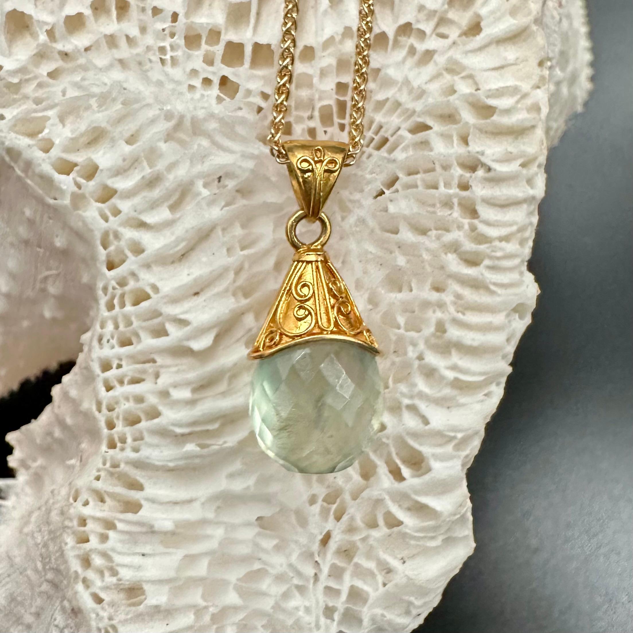 Una rilassante goccia di prehnite australiana sfaccettata di 9 x 14 mm, di colore verde pallido, è avvolta in una guaina d'oro 22K lavorata artigianalmente e decorata con un delicato motivo a spirale in questo elegante ciondolo.  Alcuni ritengono