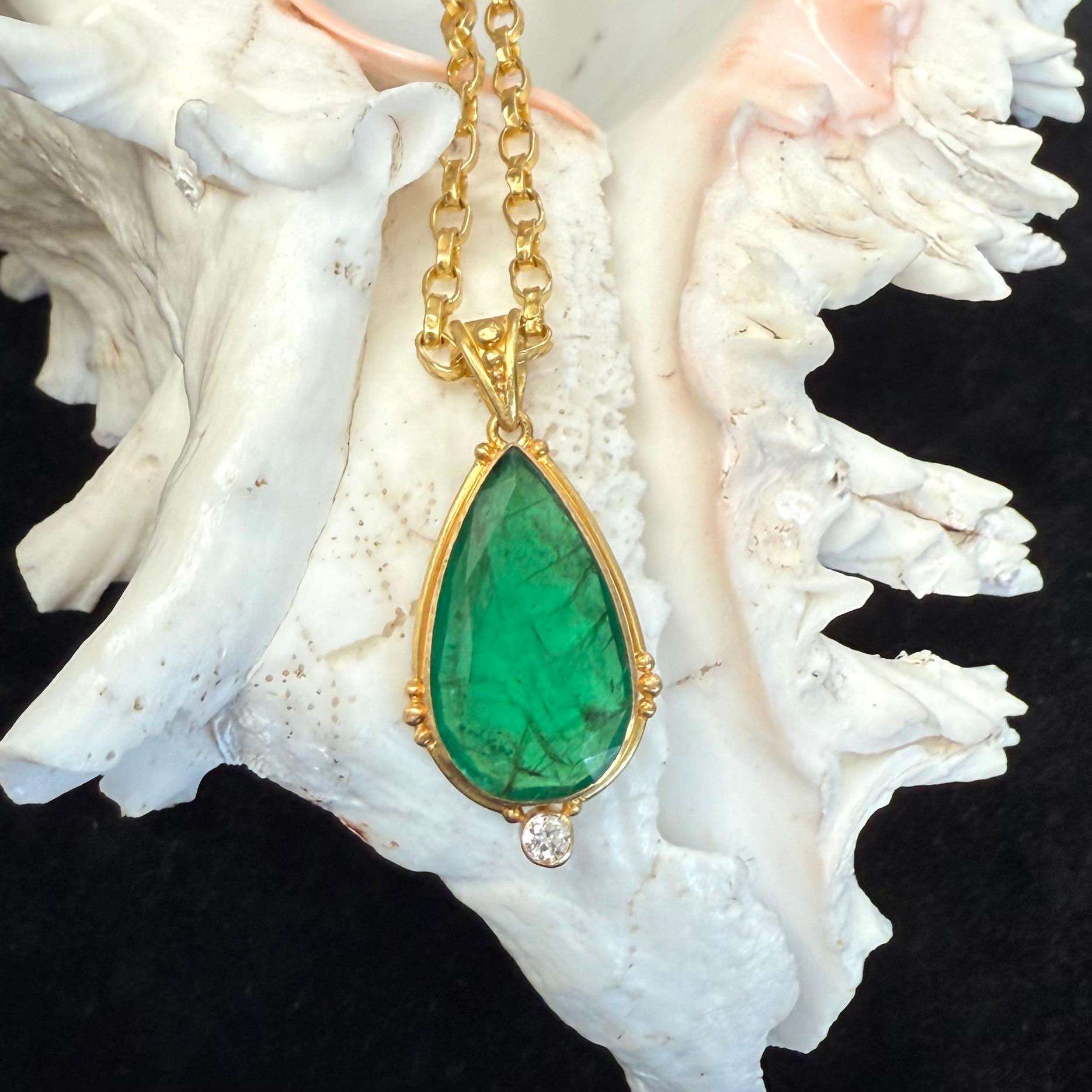 Una esmeralda verde brillante de Zambia facetada en forma de pera de 12 x 21 mm está engastada en un bisel artesanal de 18 quilates rodeado de alambre redondo y múltiples granulaciones 