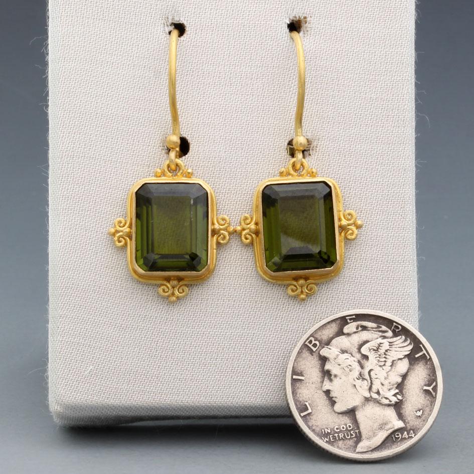 Due chiare e vivaci (e sostanziali) tormaline verdi ottagonali sfaccettate di 8 x 10 mm sono incastonate in queste bellezze delicatamente decorate con 