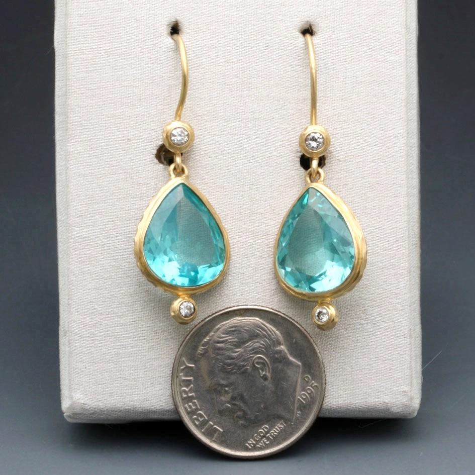 Two bright, sea-blue 9 x 13 mm pear-shaped faceted apatites are set in matte-finish 18K gold between sparkling 1.8 and 2 mm VS1 diamonds, both surrounded by wide gold bezels in this impressive and perfectly balanced design on safety-clasp wires. 