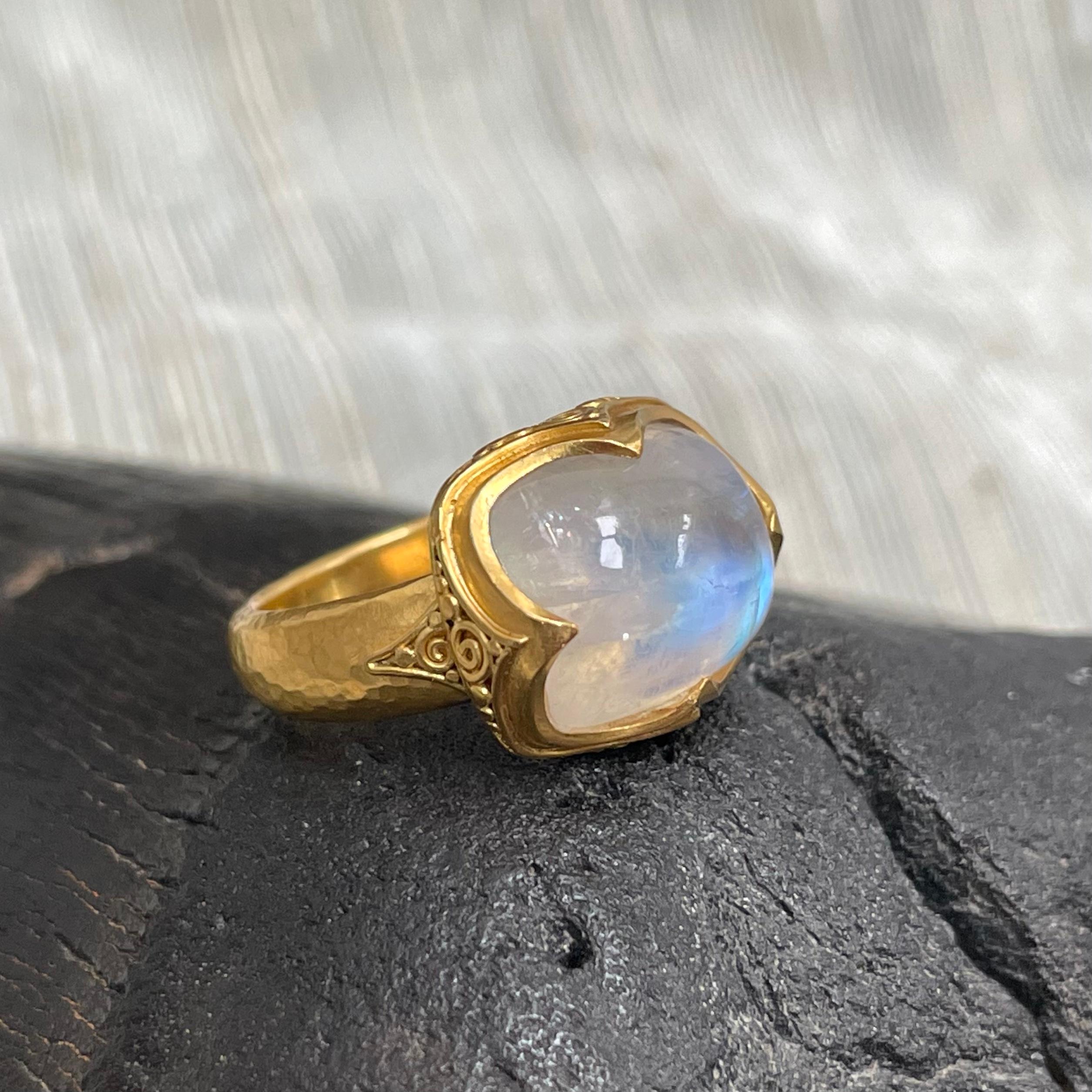 A magical and luminescent cushion shaped 10 x 14 mm rainbow moonstone cabochon is set sideways in a handmade high carat 