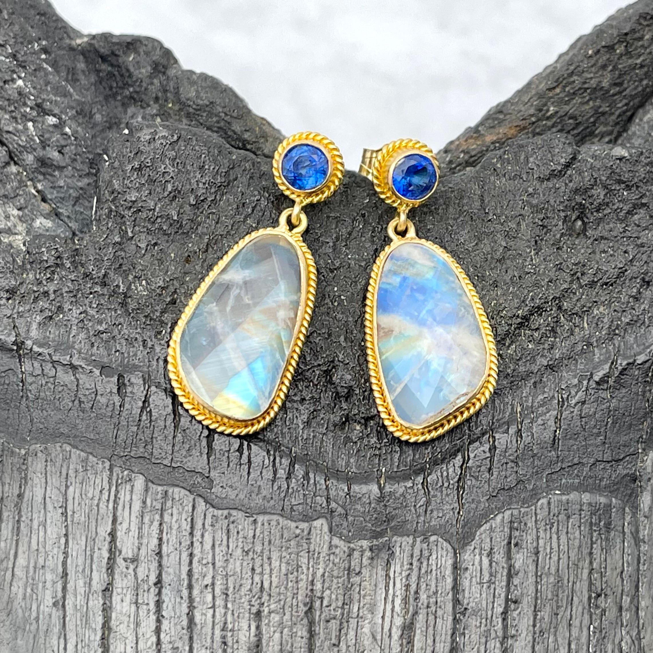 Two 8 x 15 mm irregular shaped rainbow moonstone rose cuts are suspended below intense blue 4 mm faceted Kyanite posts, all surrounded by 18 K gold twist wire accents in this attractive handmade Steven Battelle design. The hues of blue and gold
