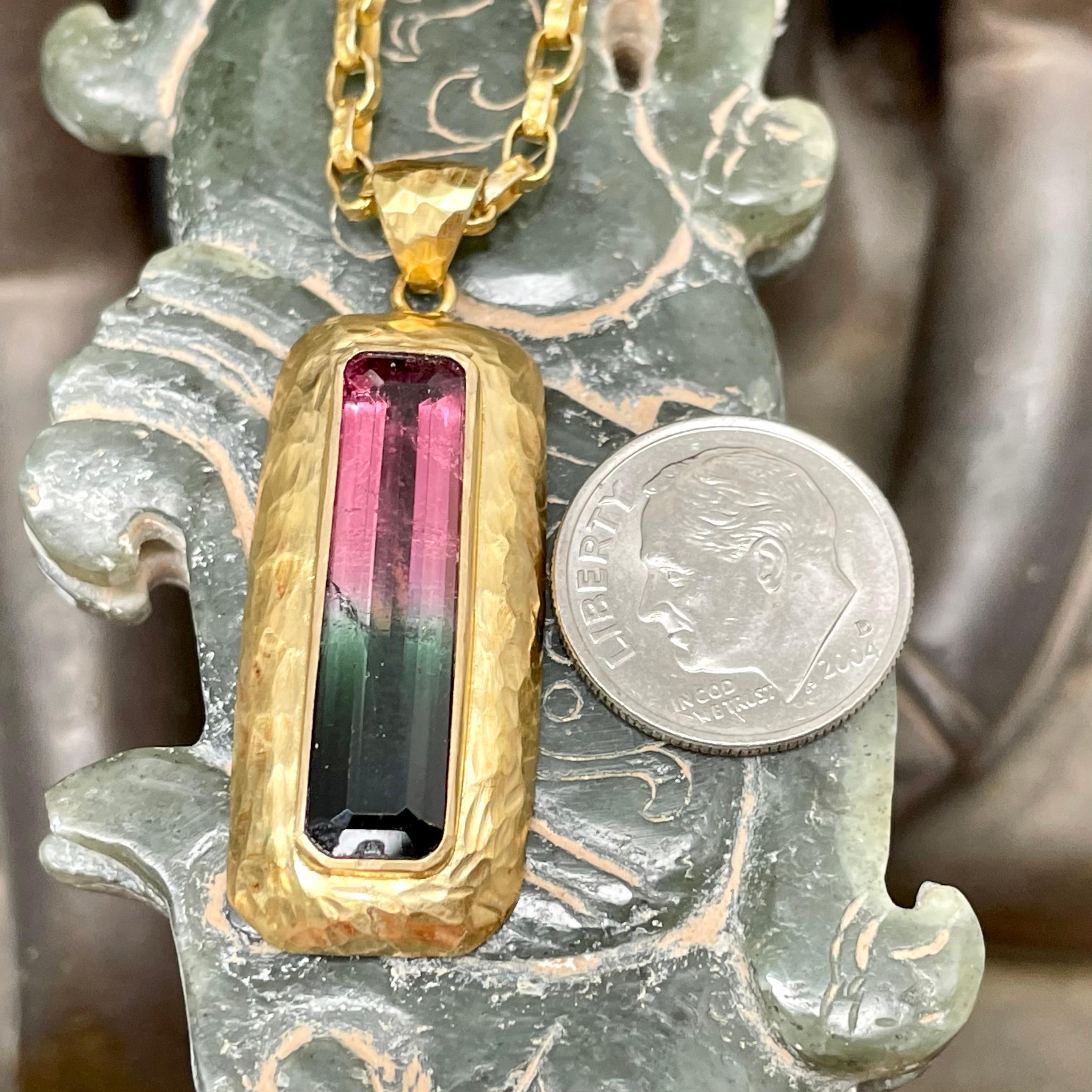 A long octagonal faceted 7 x 26 mm Brazilian Minas Gerais region watermelon tourmaline is surrounded by a wide organic hand hammered 18K gold bezel in this ultimately simple yet striking hand fabricated setting. Beautiful pink to green gradation in