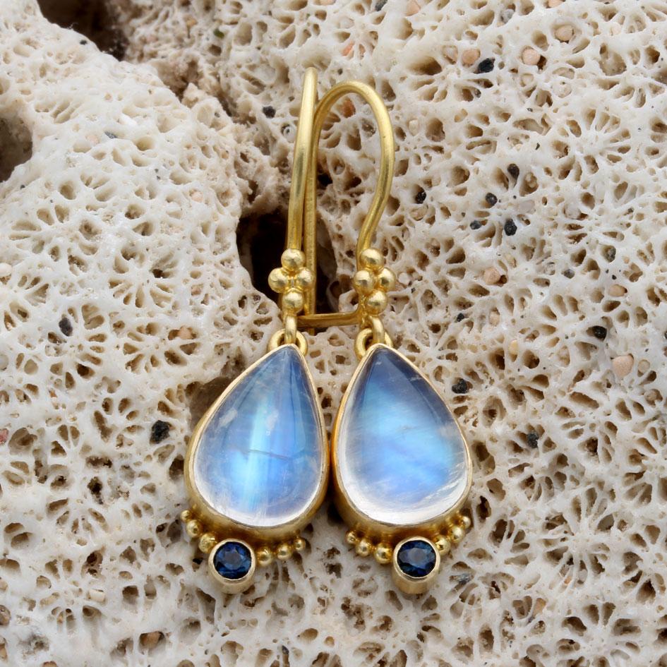 Two lively 8 x 12 mm pair shaped rainbow moonstone cabochons are set in artisan crafted 18K gold bezels and dangle below 