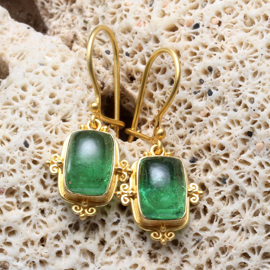 Two brilliant green 7 x 10 mm cushion shaped tsavorite cabochons are held in artisanally crafted 