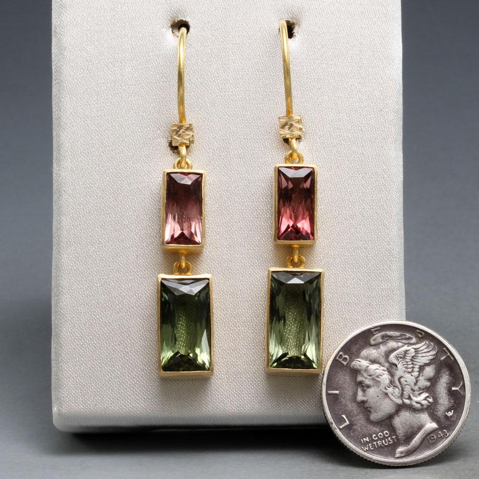 6 x 12 mm baguette-cut green tourmalines dangle below complimentary 5 x 10 mm pink tourmalines, all set in handmade matte-finish 18K gold bezels below safety-clasp wires in this attractive earring design.  Small hammered squares at the attachment to