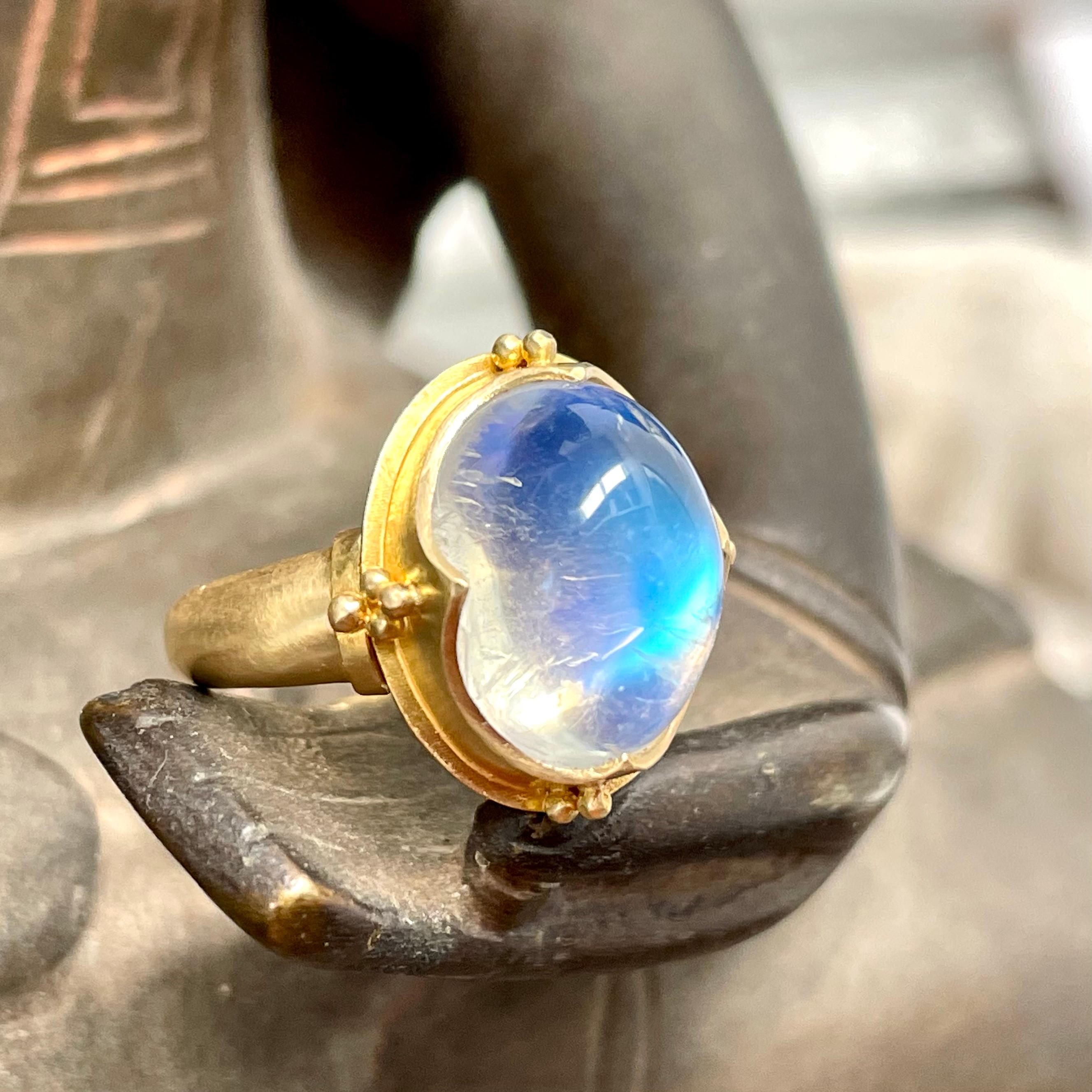 A beautiful oval 10 x13 mm rainbow moonstone cabochon is held in an ancient-inspired Steven Battelle 