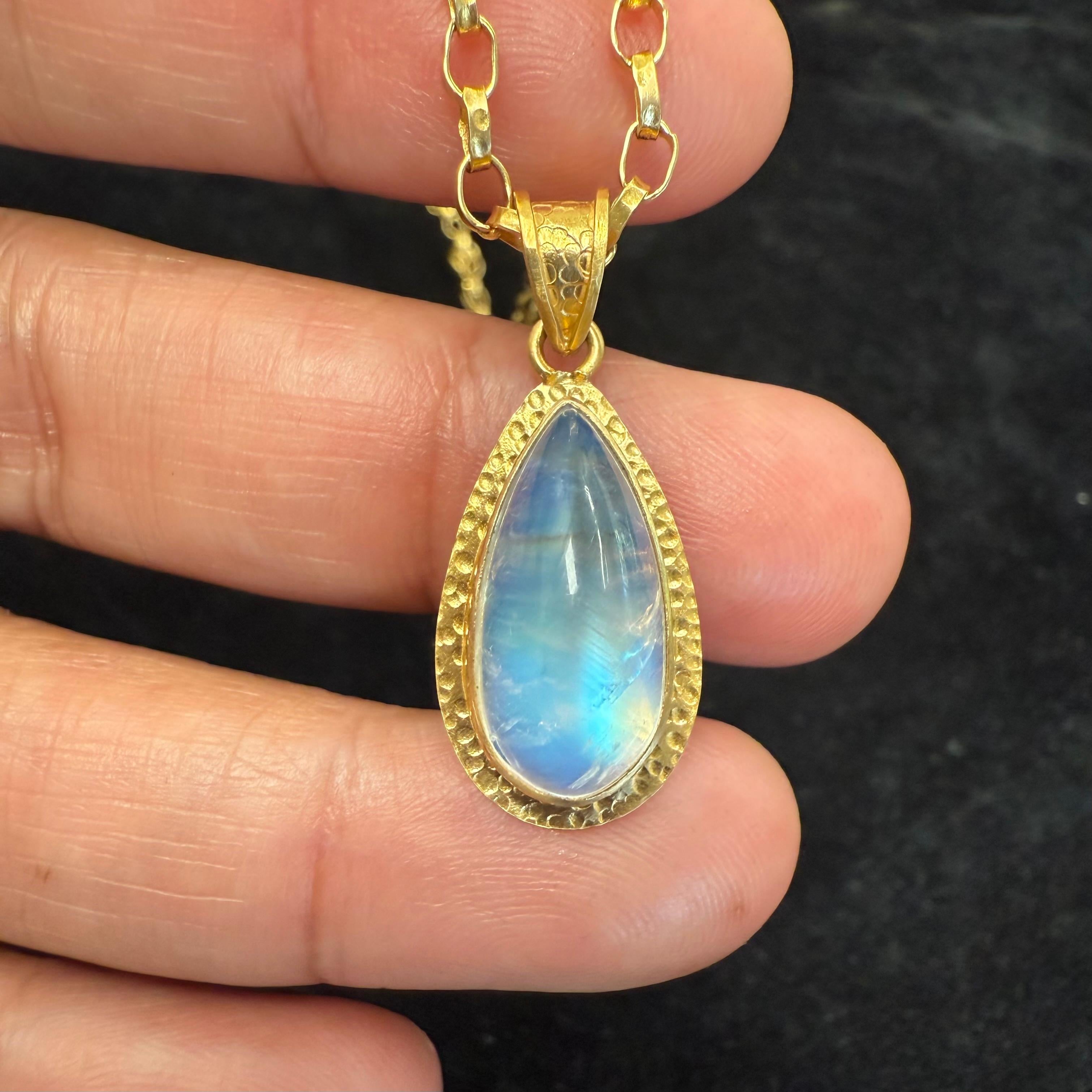 Una scintillante pietra di luna arcobaleno a forma di pera di 8 x 17 mm di lunghezza è incastonata in un doppio castone in oro 18 carati martellato a mano, con un motivo analogo sulla cava di questo grazioso ed elegante ciondolo.  Si abbina bene