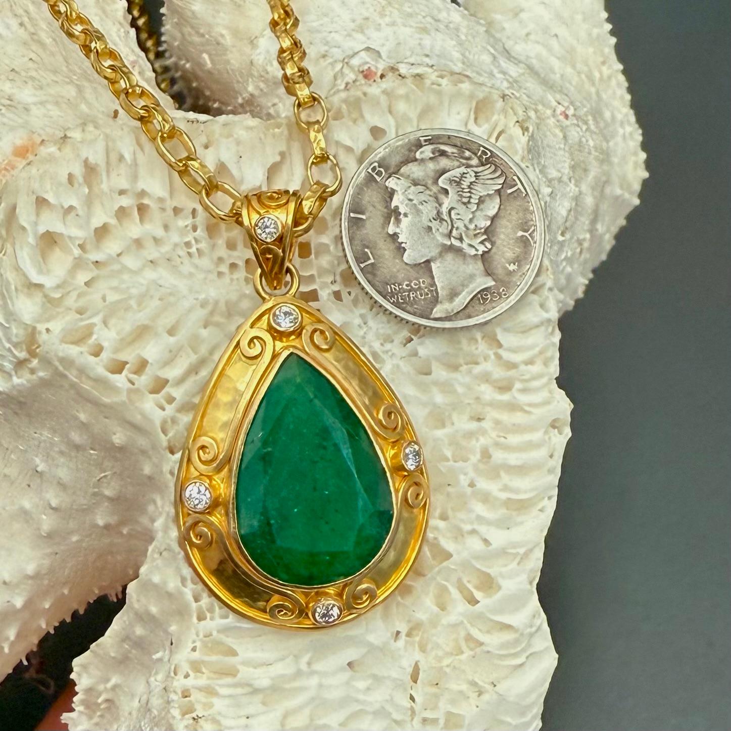 A large, 13 x 19 mm pear shaped faceted Zambian emerald is set in an ancient-inspired handmade 