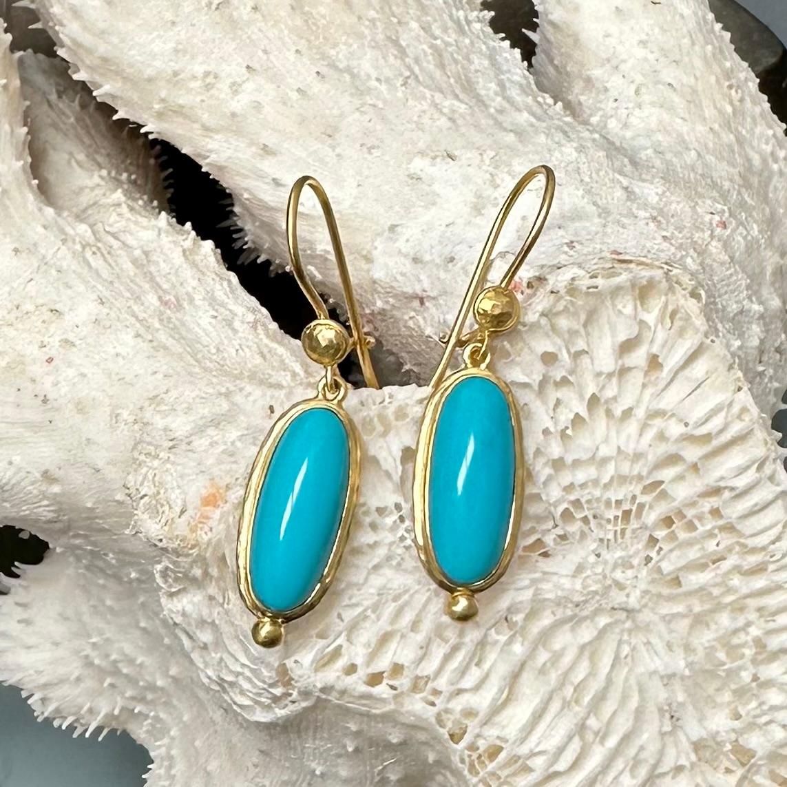 Two flawless long oval 7 x 17 mm cabochons of Arizona Sleeping Beauty mine turquoise are set in matte-finish hand hammered double bezels suspended below safety clasp 18K gold wires beneath circular discs with complementary large 