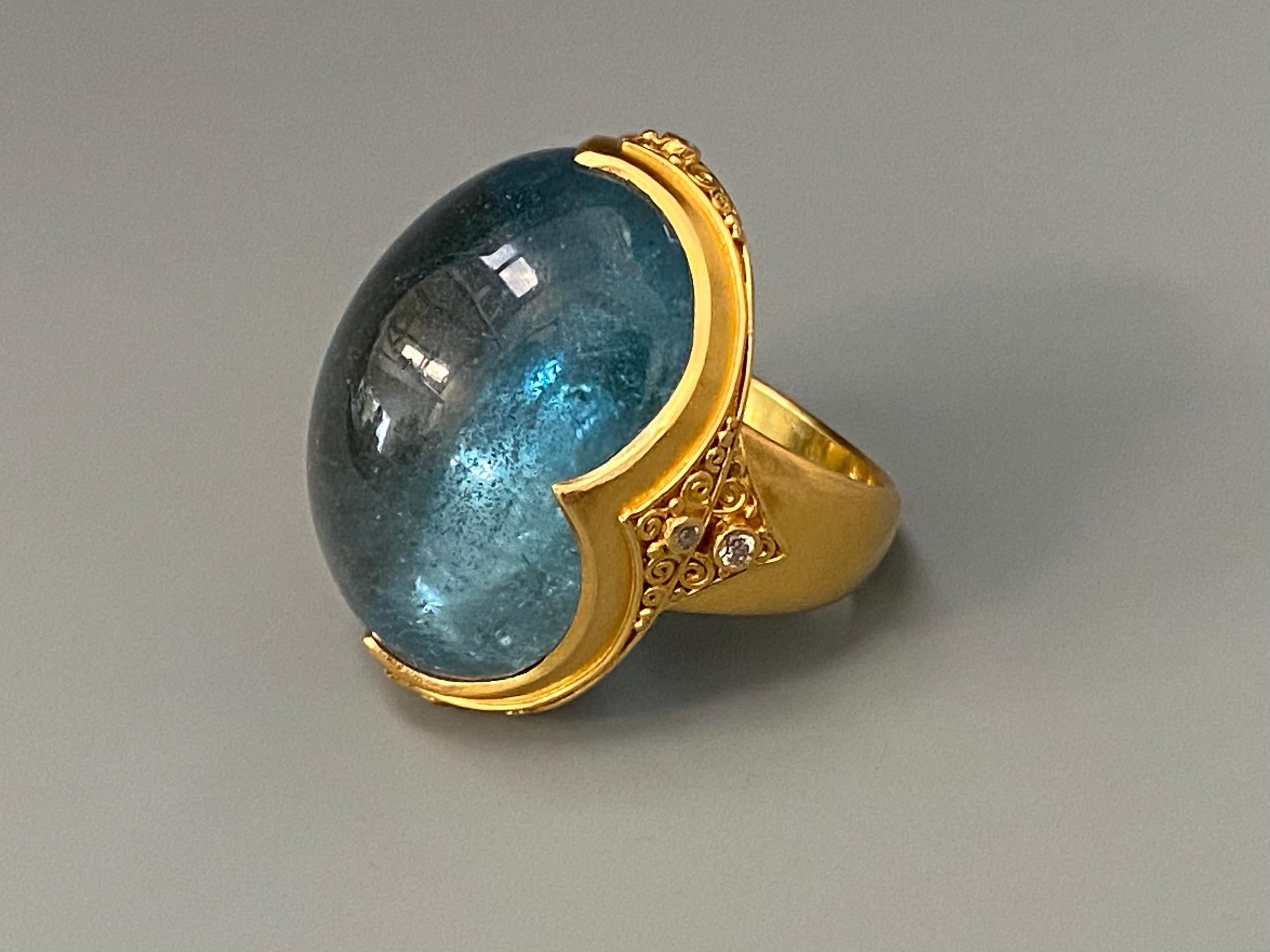 A clear, and luminous, deep blue Brazilian Aquamarine oval cabochon is set in a signature Steven Battelle ancient inspired 