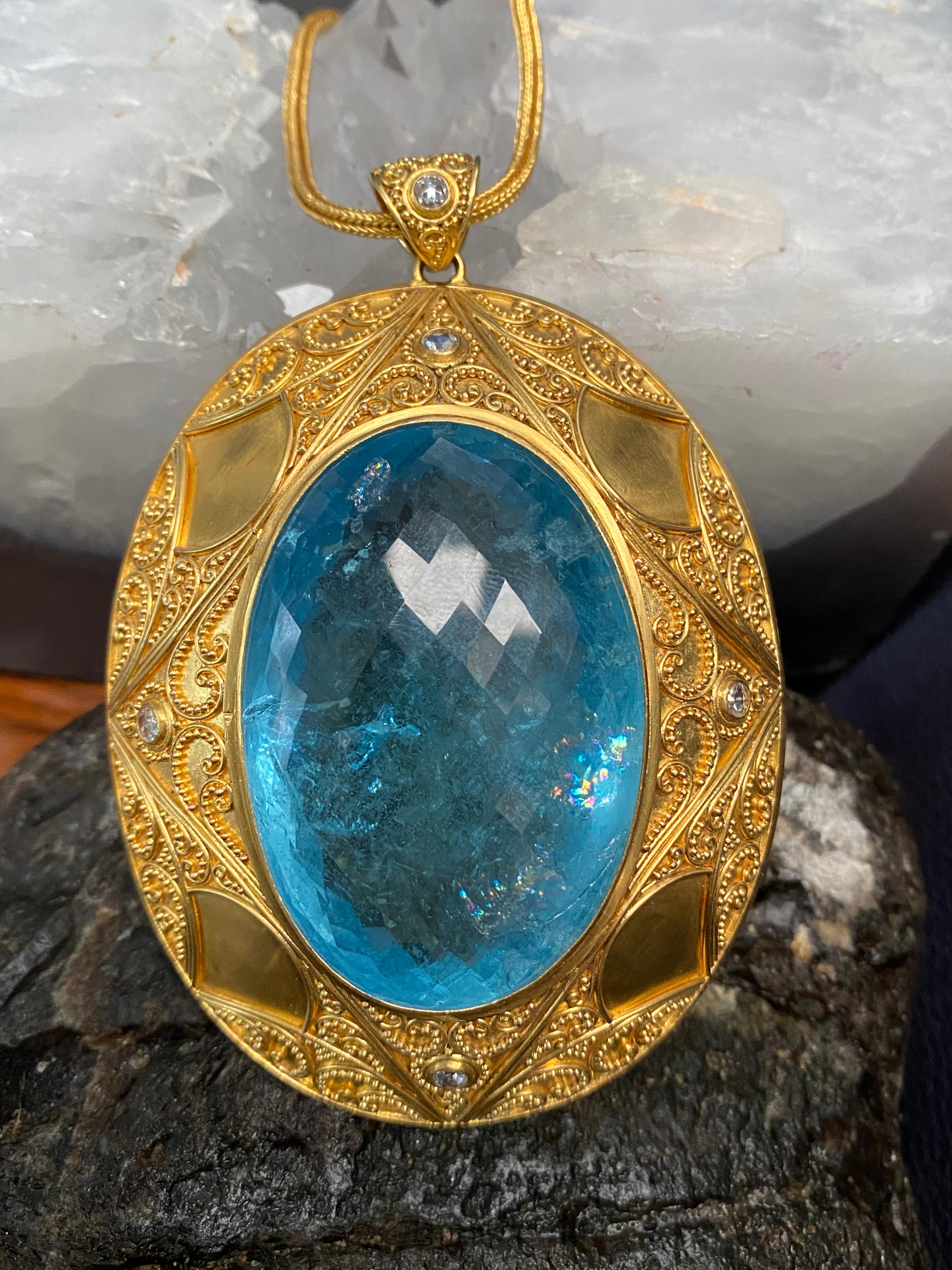 A massive 30 x 50 mm oval Brazilian Minas Gerais faceted aquamarine is the centerpiece of this truly one-of-a-kind masterpiece. 182.3 carats altogether. This amazing stone is set within a wide, intricately designed high-karat granulated setting with