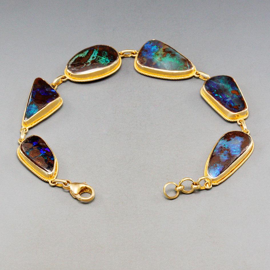Handcrafted Steven Battelle 40.3 Carat Boulder Opal Bracelet in 18K gold setting.
Beautiful Australian Boulder Opal handmade bracelet accented with extended bezel is a must add to your collection.
Stones size 10x14mm approx.
Weight 16.85 gram
Length
