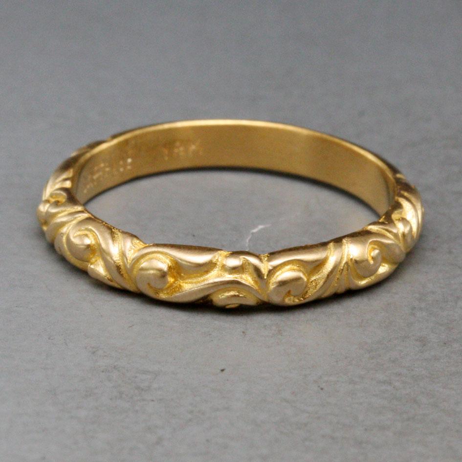 A mid-weight 4 mm wide 18K gold shank is graced with multiple intertwined large and small swirls in this wonderful example of the wax carvers artistry.  A nice interplay of gleaming curves and shadows on the hand. This particular ring is size 7, but
