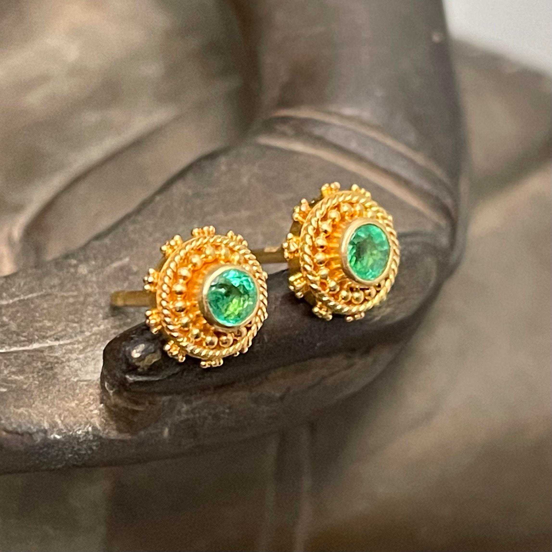 Two bright green 3mm faceted Columbian emeralds are set in delicate twist wire and granulation in these delightful post earrings. Truly fine gold-smithing went into the creation of these small treasures.  