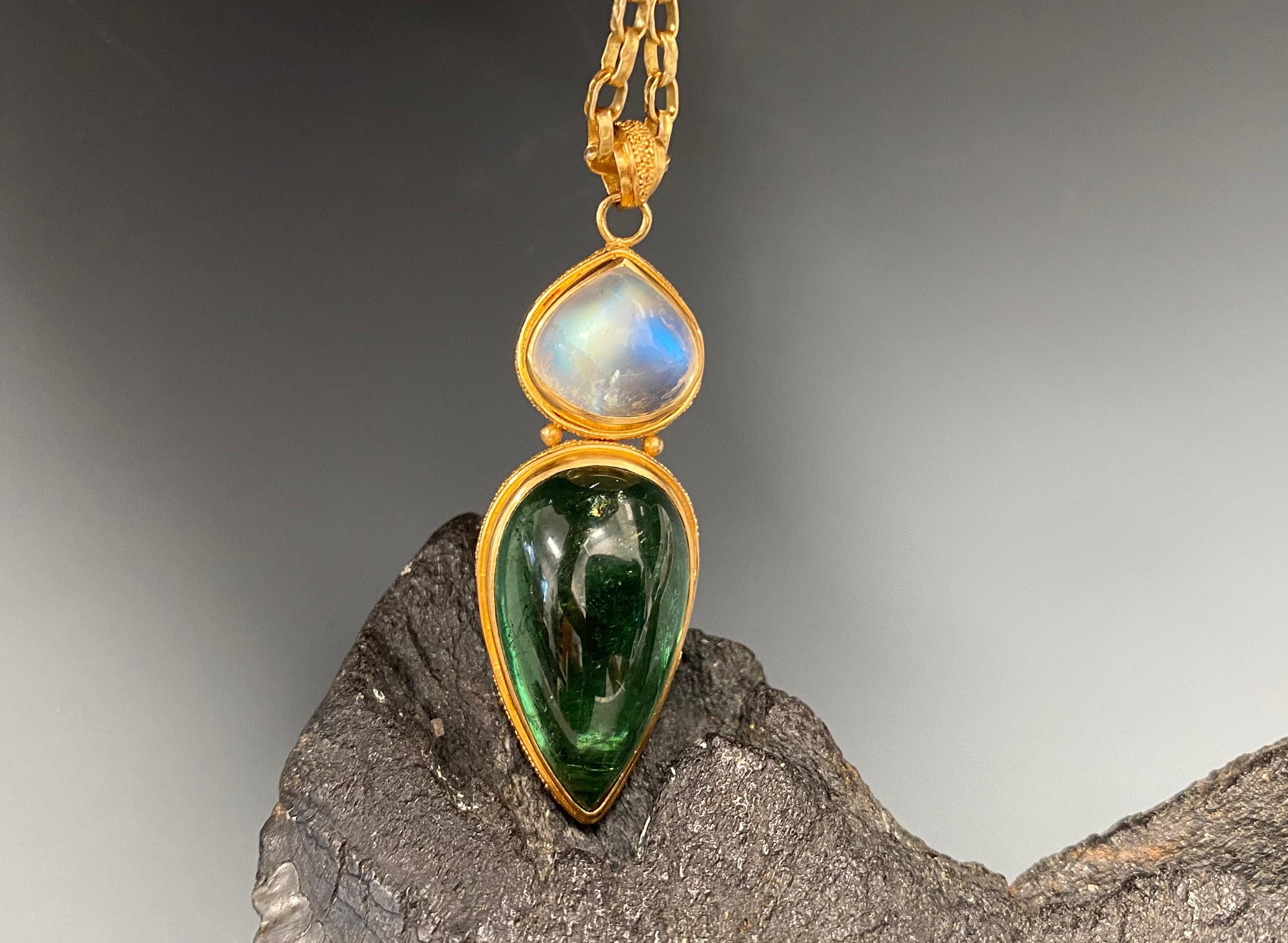 Two opposing complementary colored pear cabochon stones are ornamented with delicate 