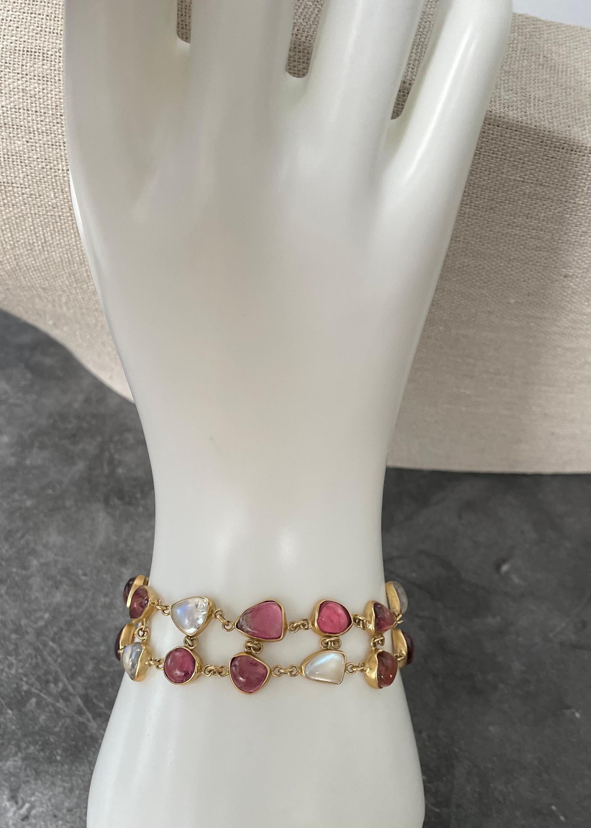 A combination of 20 organically shaped cabochons of mixed pink tourmaline and rainbow moonstone approximately 5 x 7 mm in size are handset in simple 18K bezels and joined in two rows in this sweet 18K toggle bracelet.  Matte-finish. This bracelet is