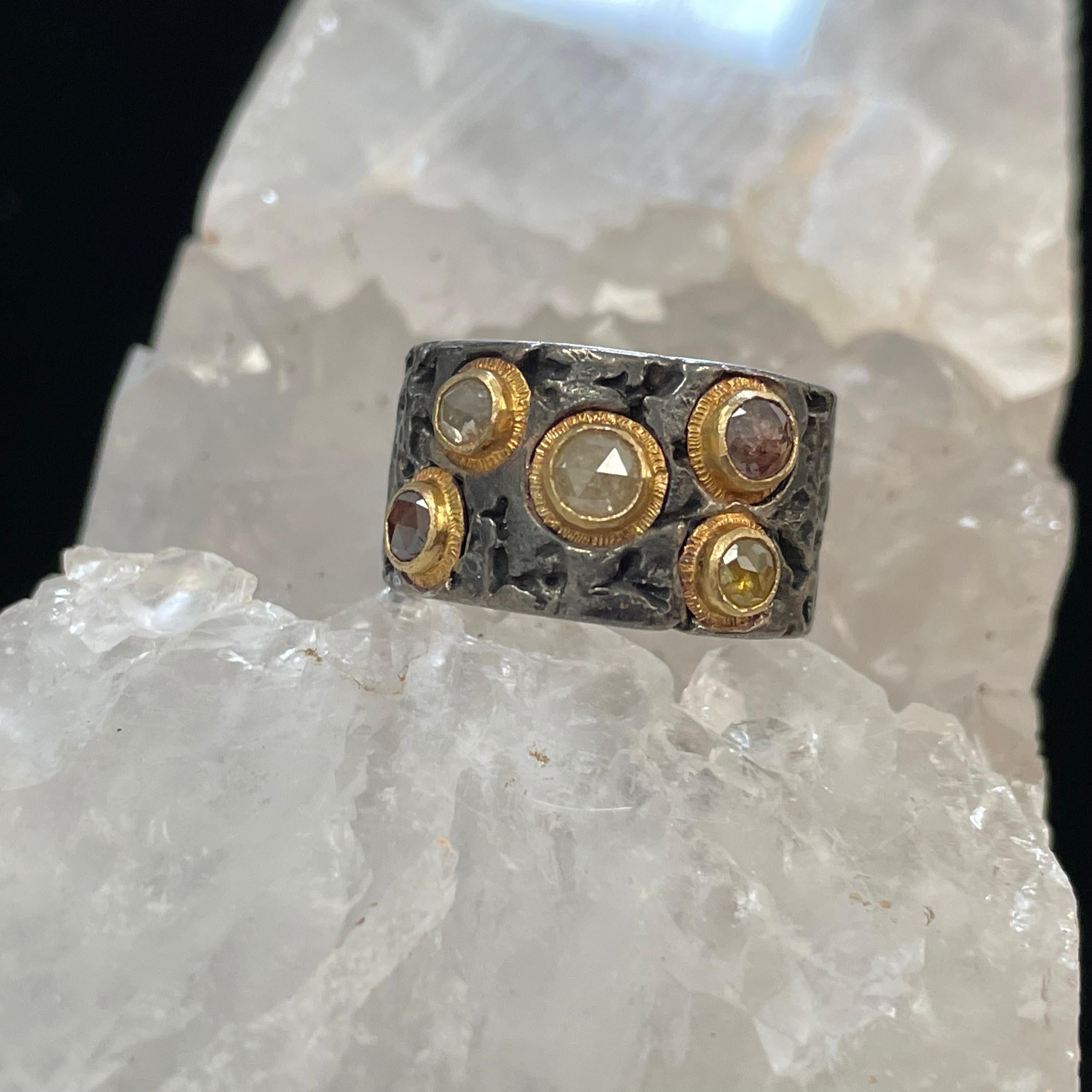5 multi-colored and multi-sized (3-4 mm) diamonds totaling 1.1 carats are set with line textured 18K bezel accents into this organic oxidized silver and 18K gold Steven Battelle design.  This particular ring is sized 6, and is not resizable.  We can