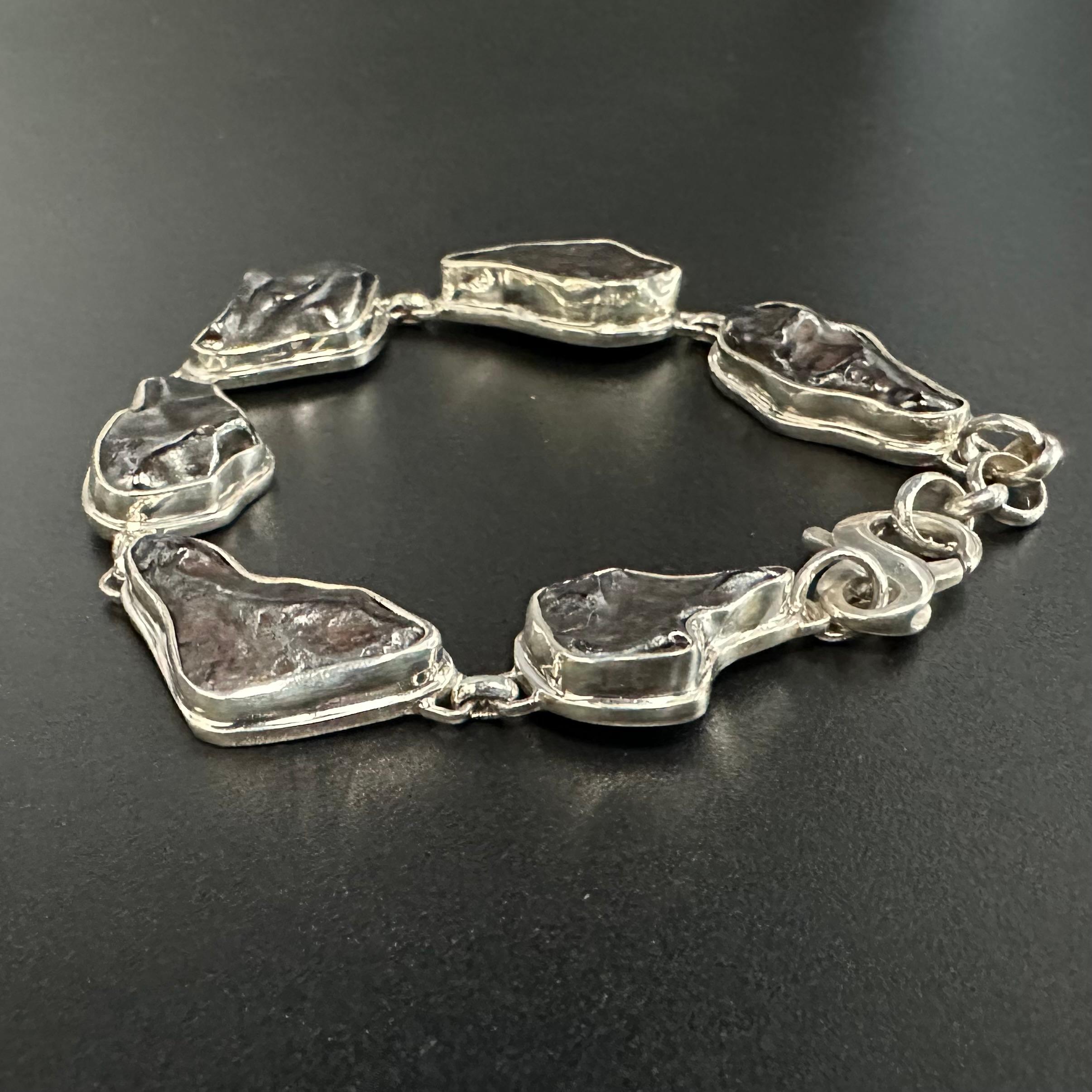 Six roughly 10 x 22 mm fragments of the Sikhote-Alin Meteorite are held in thick handmade sterling silver bezels with double bezel accents below, and linked, to create this unique 