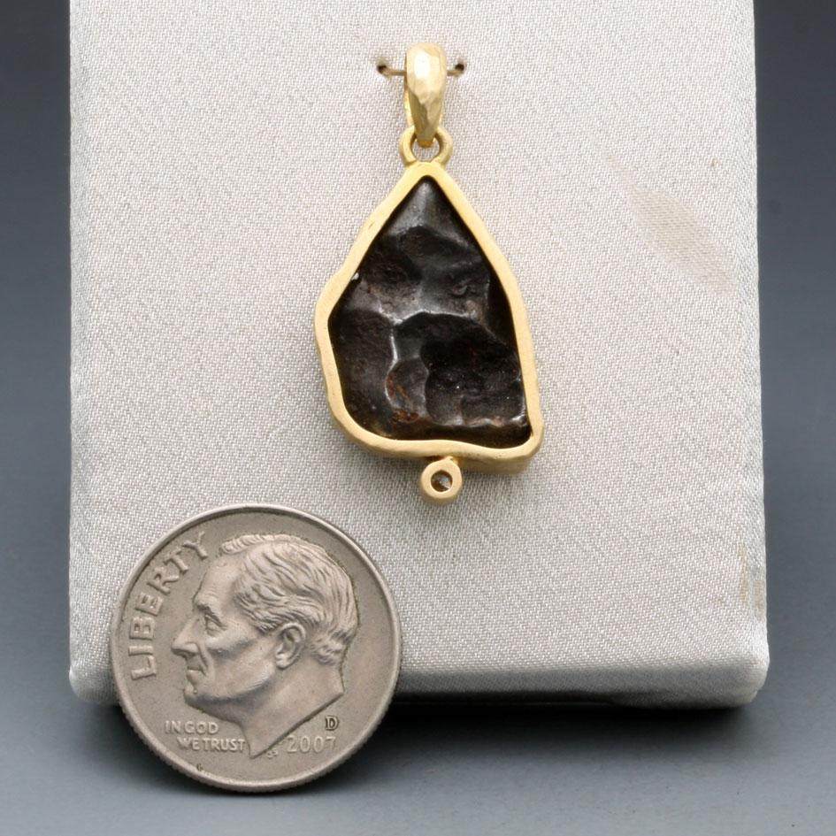 A somewhat irregular 11 x 19 mm irregular shaped fragment of Sinkote-Alin meteorite with a fusion crust from its flaming entry through the atmosphere is set in simple matte-finish 18K gold bezel with a 1.8 mm VS1 diamond accent below.  A large iron