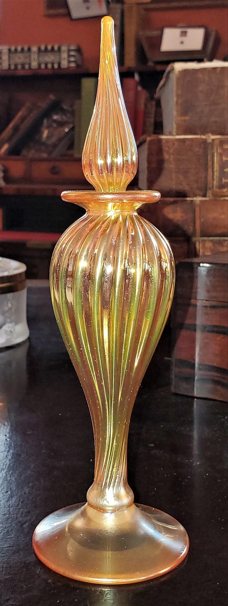 Presenting a beautiful Steven Correia art glass perfume bottle,

American, circa 1980.

Luminescent yellow/orange/gold bulbous base with ribbed detail and original ribbed and fluted stopper.

Fully signed and marked with serial numbers etc on