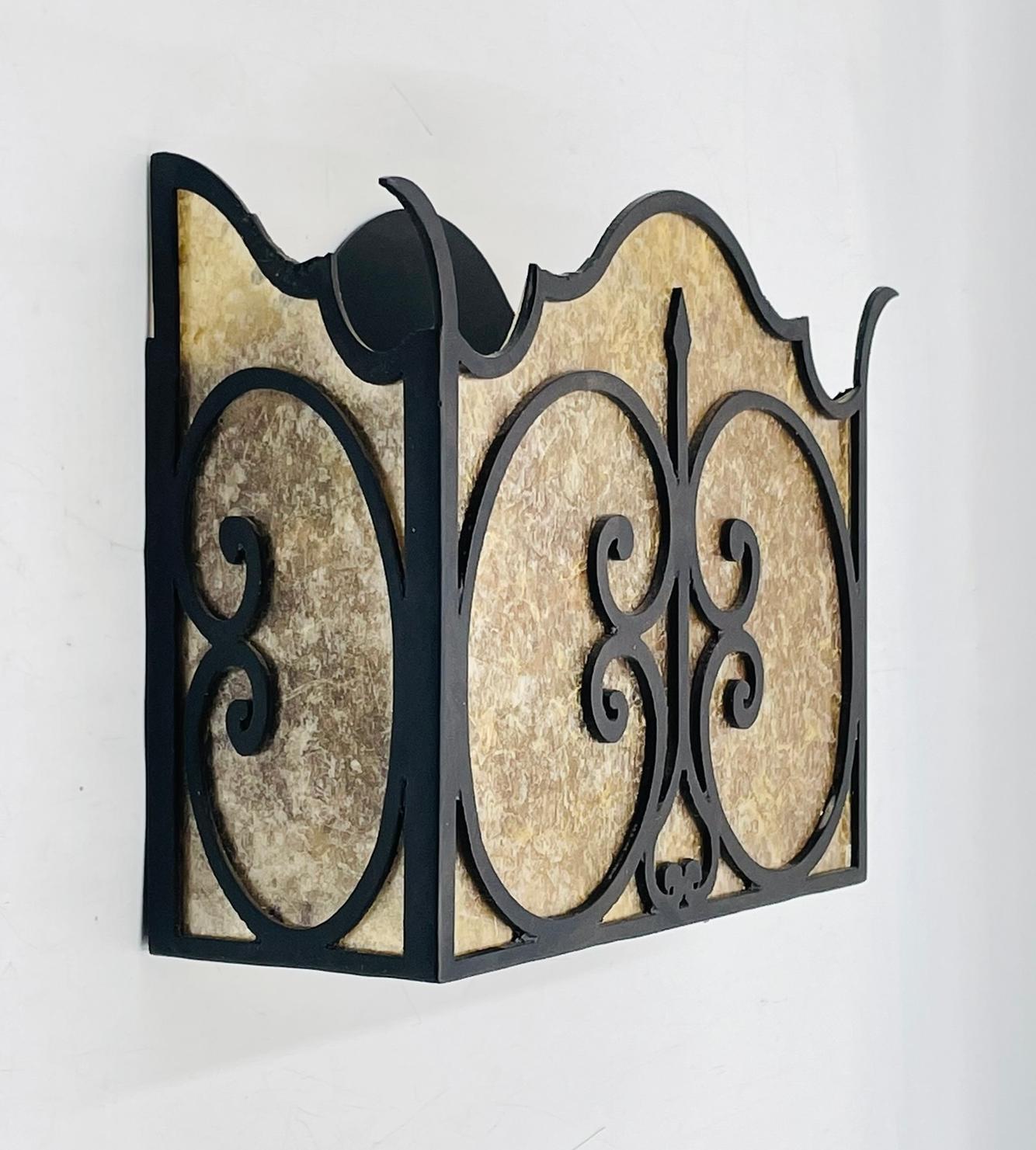 A handcrafted Spanish Revival-style wall sconce by Steven Handelman Studios, featuring a wrought iron frame with scrolled ornamentation and textured natural mica panels. The warm amber tones of the mica provide a subtle glow when illuminated,