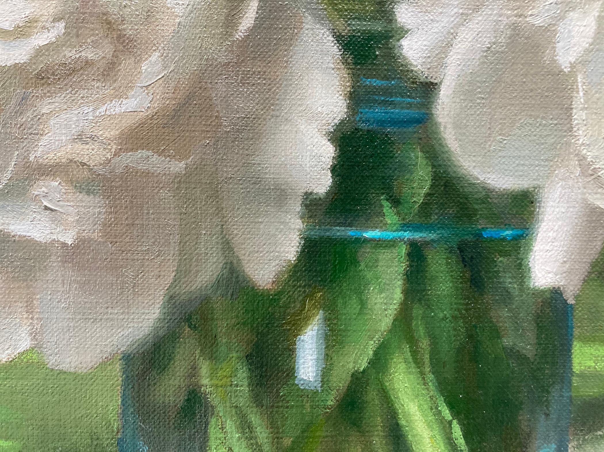 An oil painting of peonies in full bloom set against a classic trompe l'oeil background. The blue glass vase that holds the blooms sits on a granite or slate ledge on top a neutral tan drape, one flower on lays on the drape next to the vase. The cut