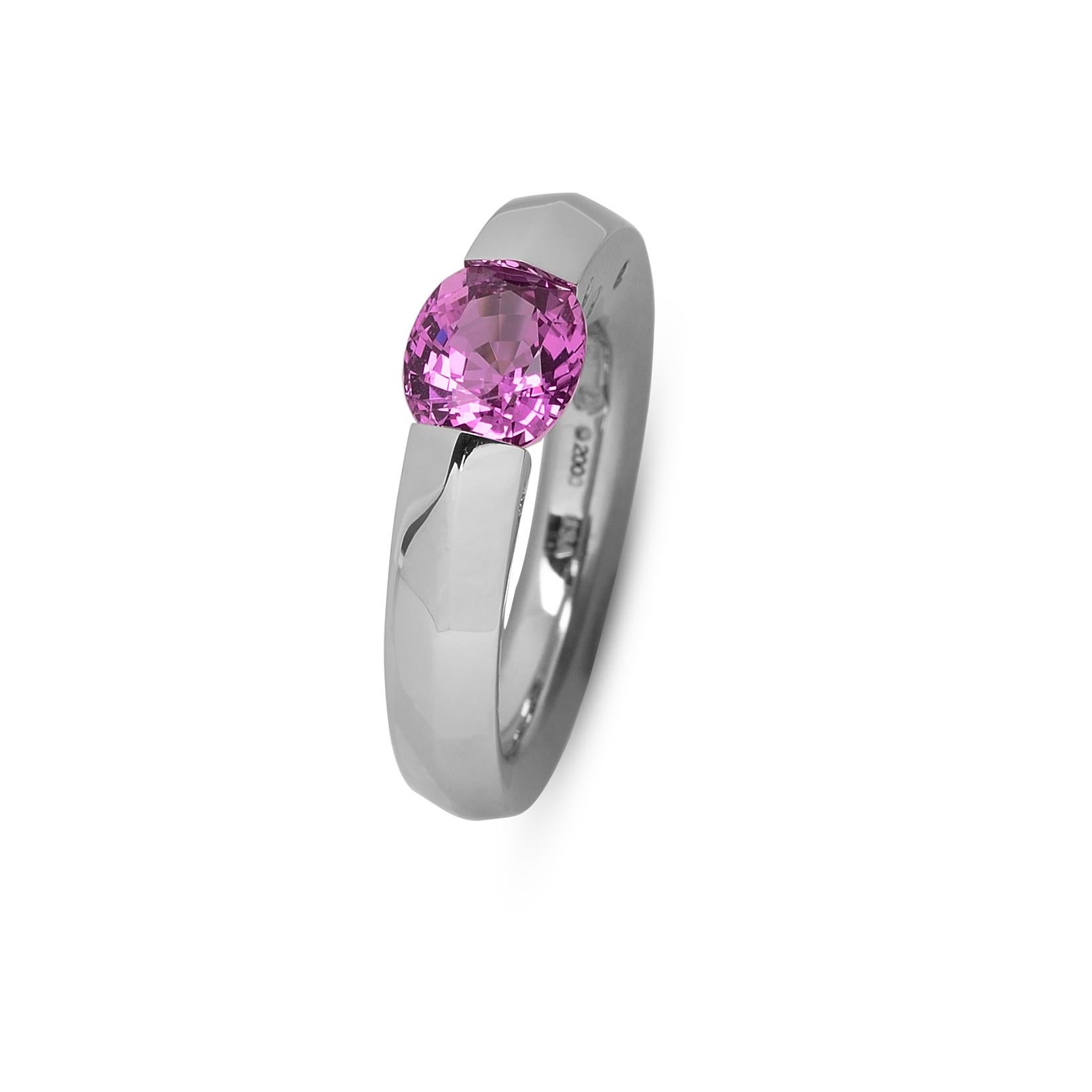 The Steven Kretchmer Blade ring with a tension-set pink sapphire is handcrafted in platinum with a shiny top finish and matte undercut. The 2.15 ct. oval cut sapphire is a saturated bubblegum pink which in different lighting  can have an almost
