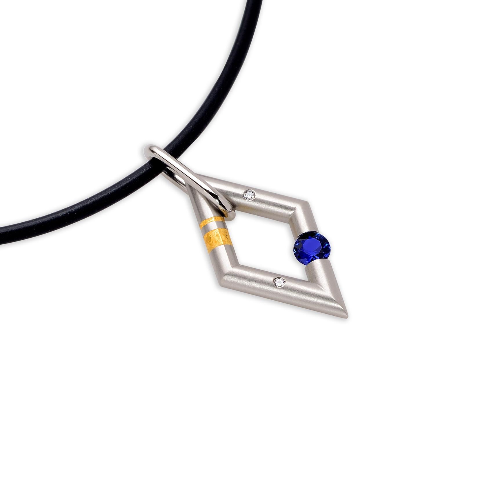 The Steven Kretchmer Diamond Shaped Pendant with a tension-set blue sapphire is handcrafted in satin platinum with a shiny platinum bail and 24K crystalized gold inlay. The 0.28 ct. blue sapphire is 4mm in diameter and is classic royal blue that