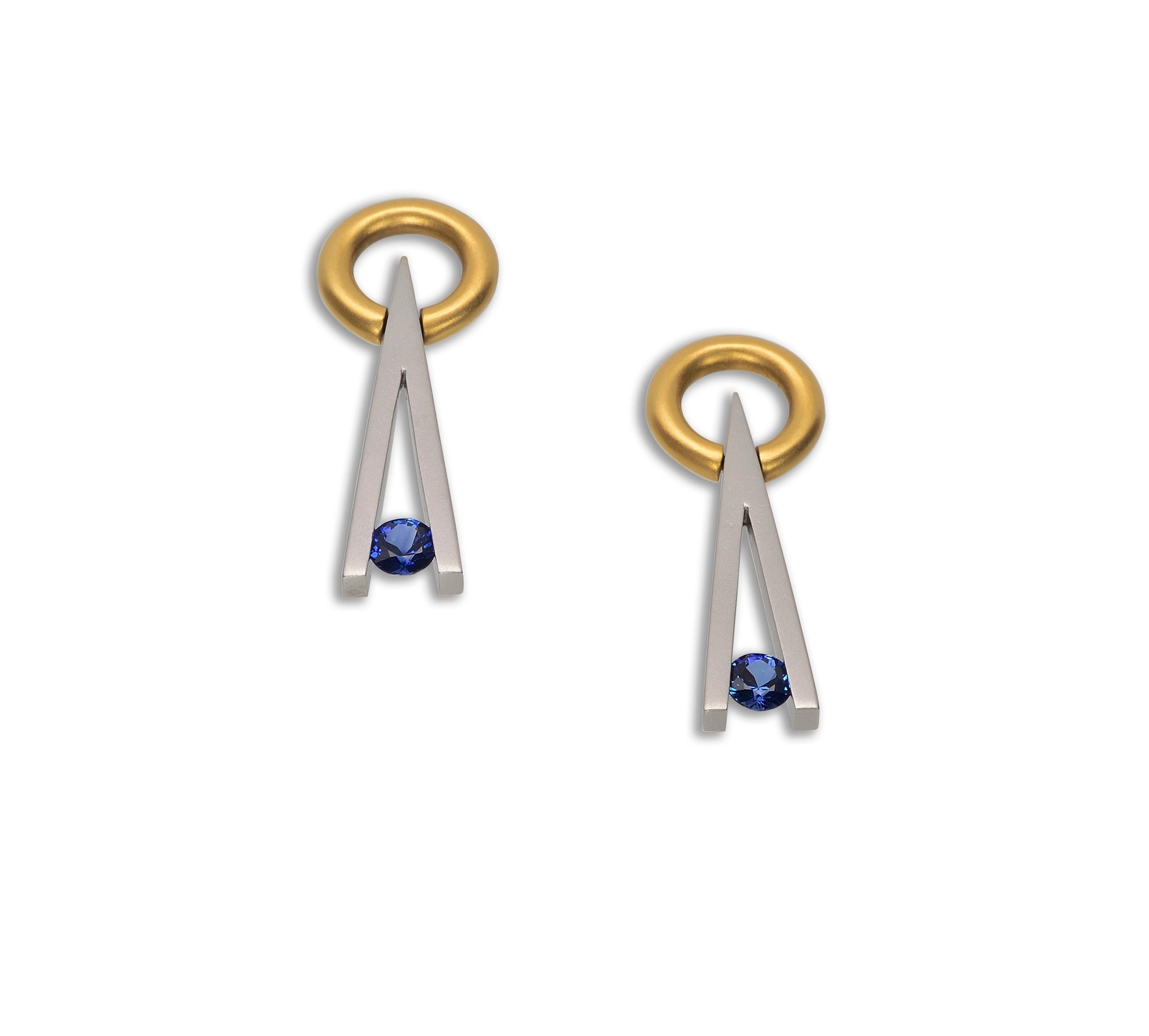 The Steven Kretchmer Swinging V earrings are handcrafted in both platinum and 18K yellow gold with a matte finish. Each earring features a tension-set round blue sapphire (0.57 ctw.). The sapphires are a vibrant royal blue. 18K yellow gold friction