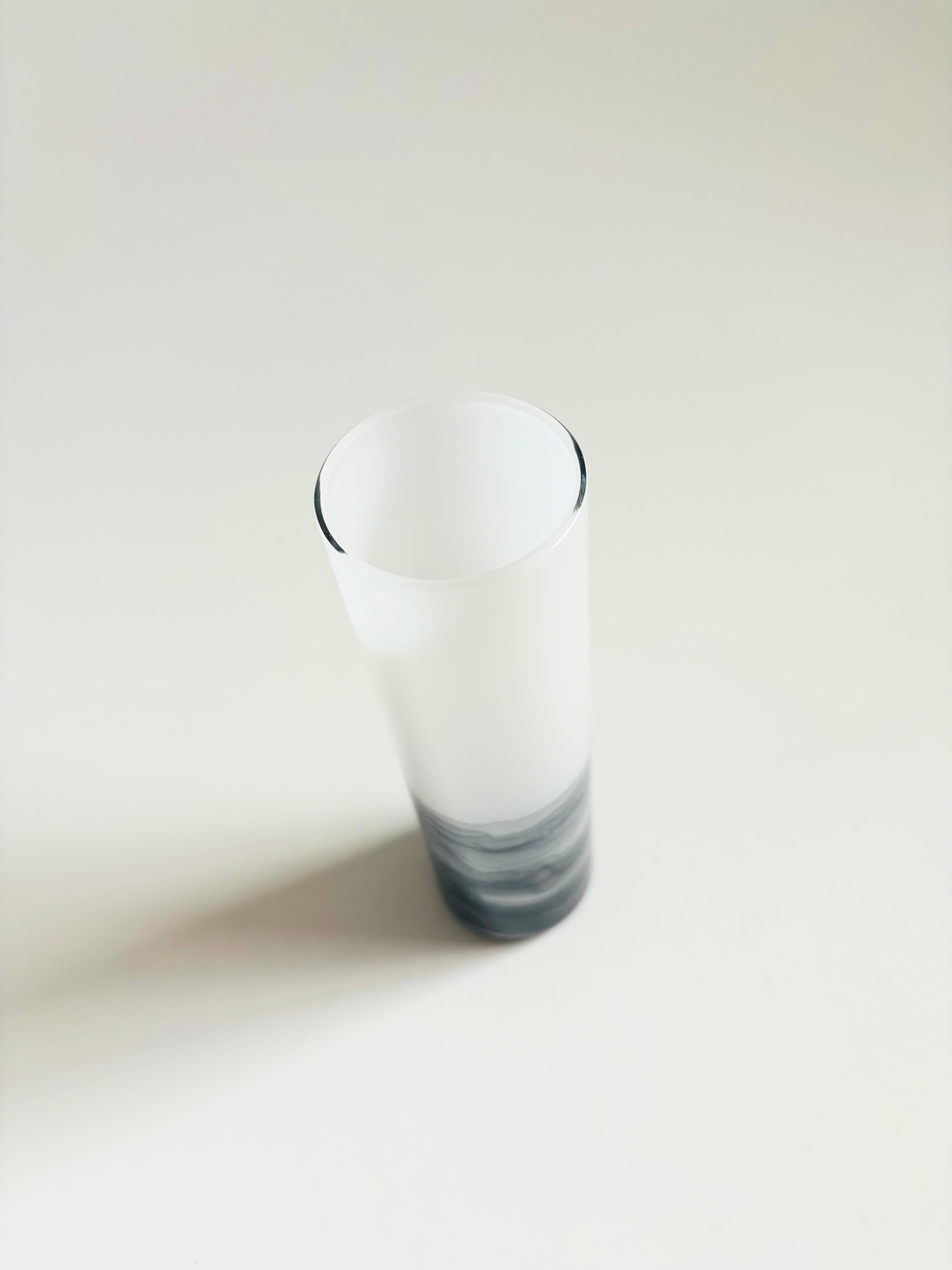 Un bellissimo vetro soffiato d'epoca dell'artista del vetro Steven Maslach. La base ha un design a vortice grigio e la parte superiore è di colore bianco latte. Una bella forma cilindrica semplice. Firmato sulla base e sembra essere datato 1988.

