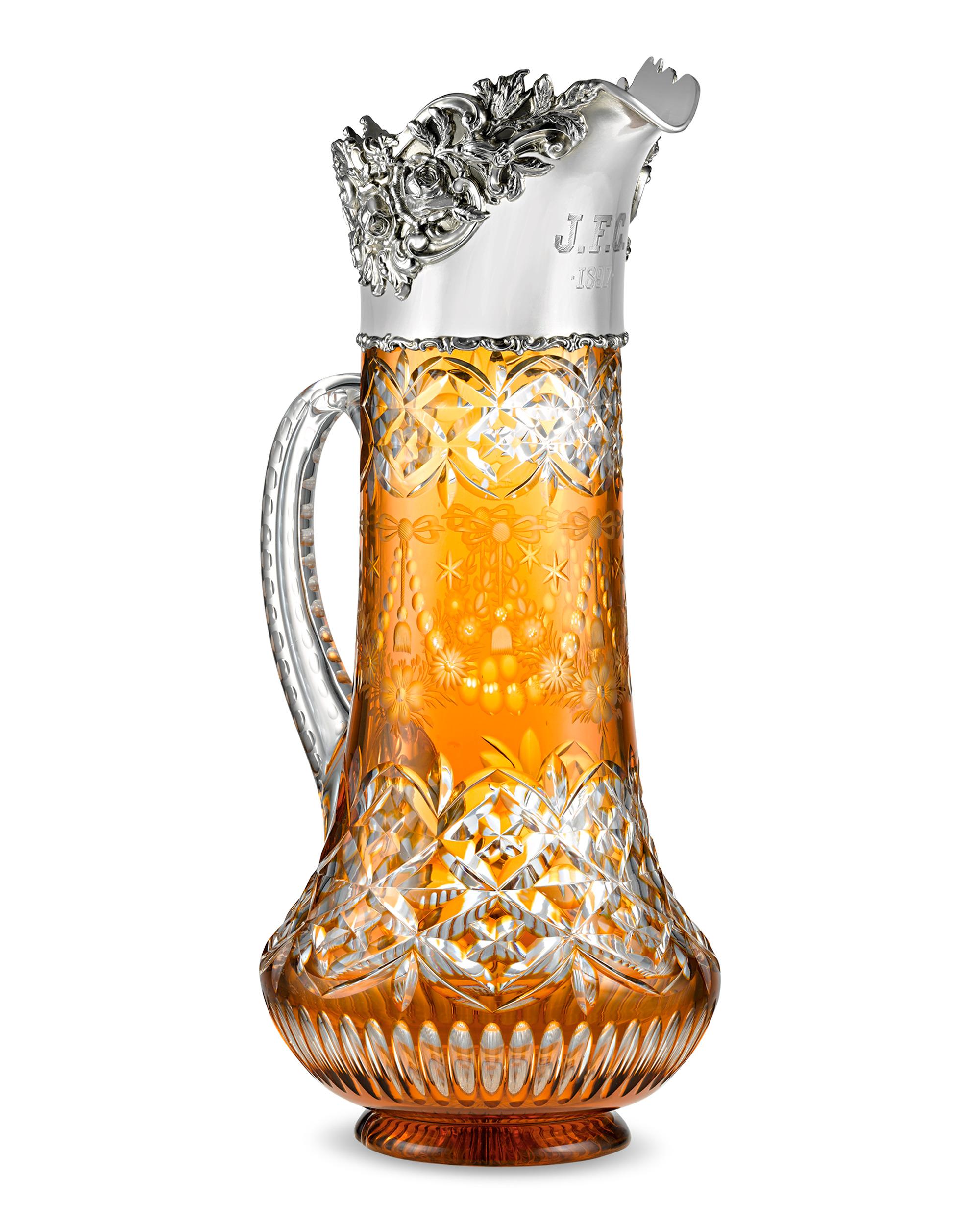 This stunning and rare jug by renowned British glassmakers Stevens & Williams features an exquisite butterscotch Cut to Clear design with scrolling foliate motifs. Beyond its coveted orange color, the jug's sterling silver rim by Philadelphia-based