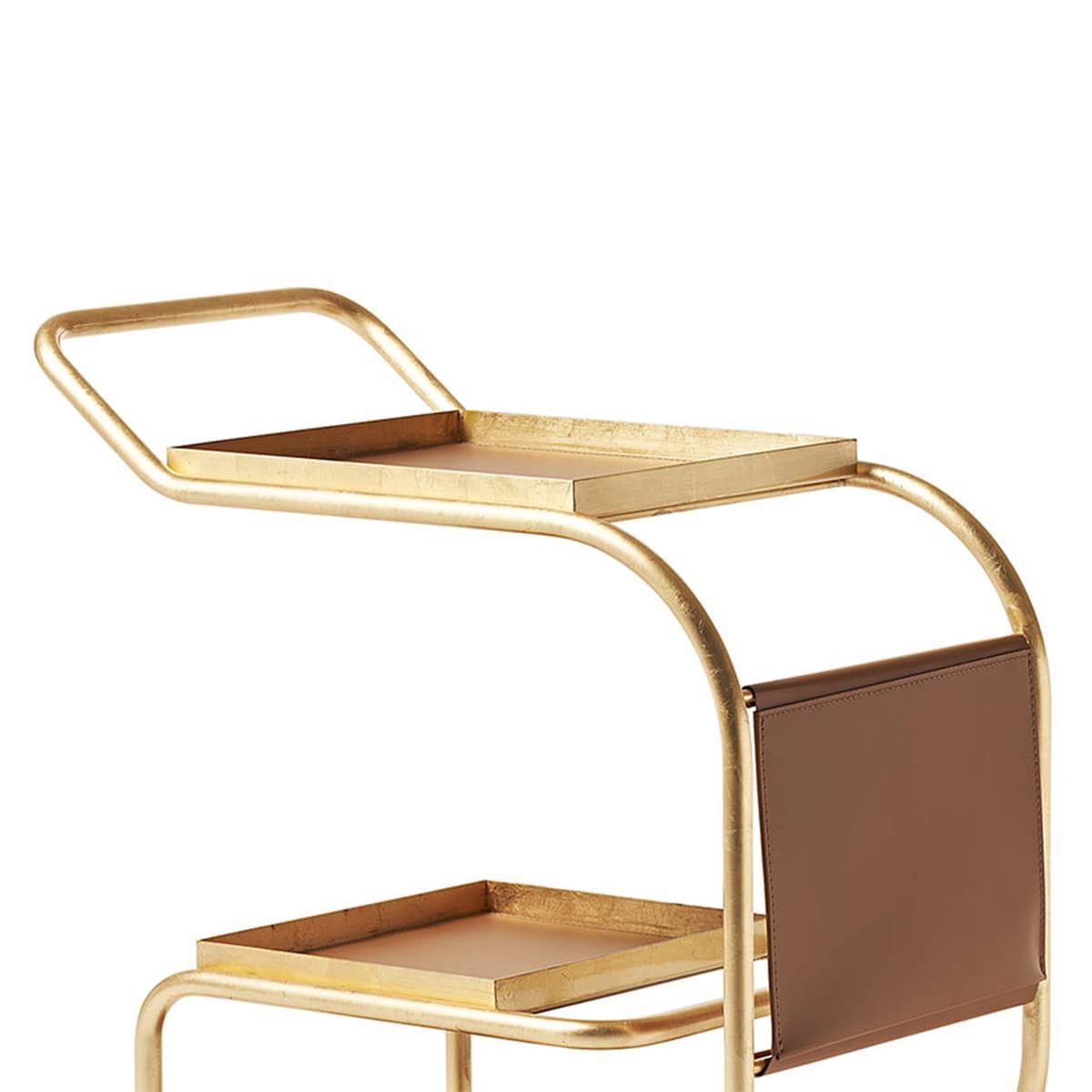 Trolley Stewart Gold with steel structure in gold leaf
Finish, with steel trays covered with natural brown leather 
And with newspaper pocket. 2 of the trays are removable.
Trolley with 4 pivoting casters.
Also available in white matte finish or