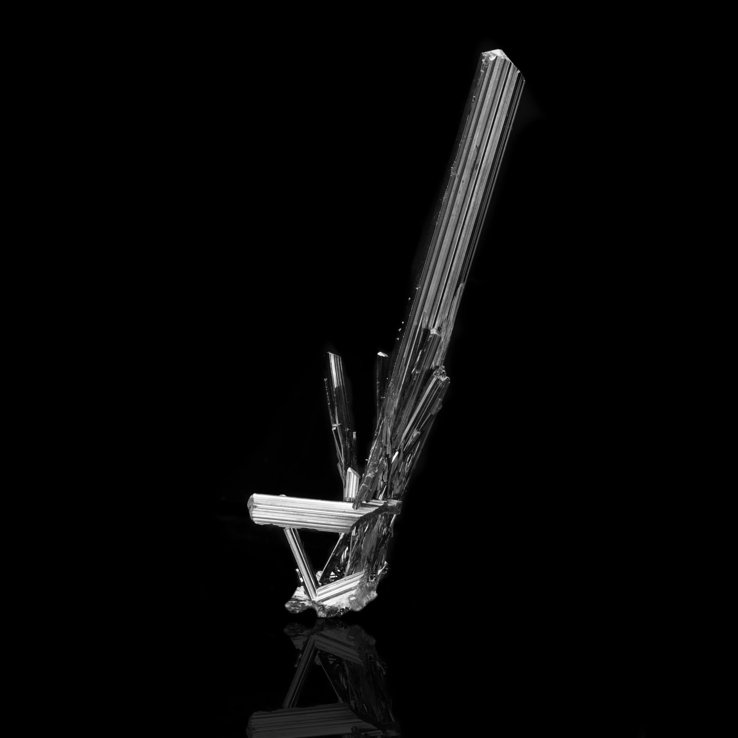 This long, nearly mirror-lustrous, thickly striated stibnite crystal from China set off by moderately sized accenting stibnites comes to a huge, perfect termination. An impressive and fully intact cluster mounted on a lucite base for ready
