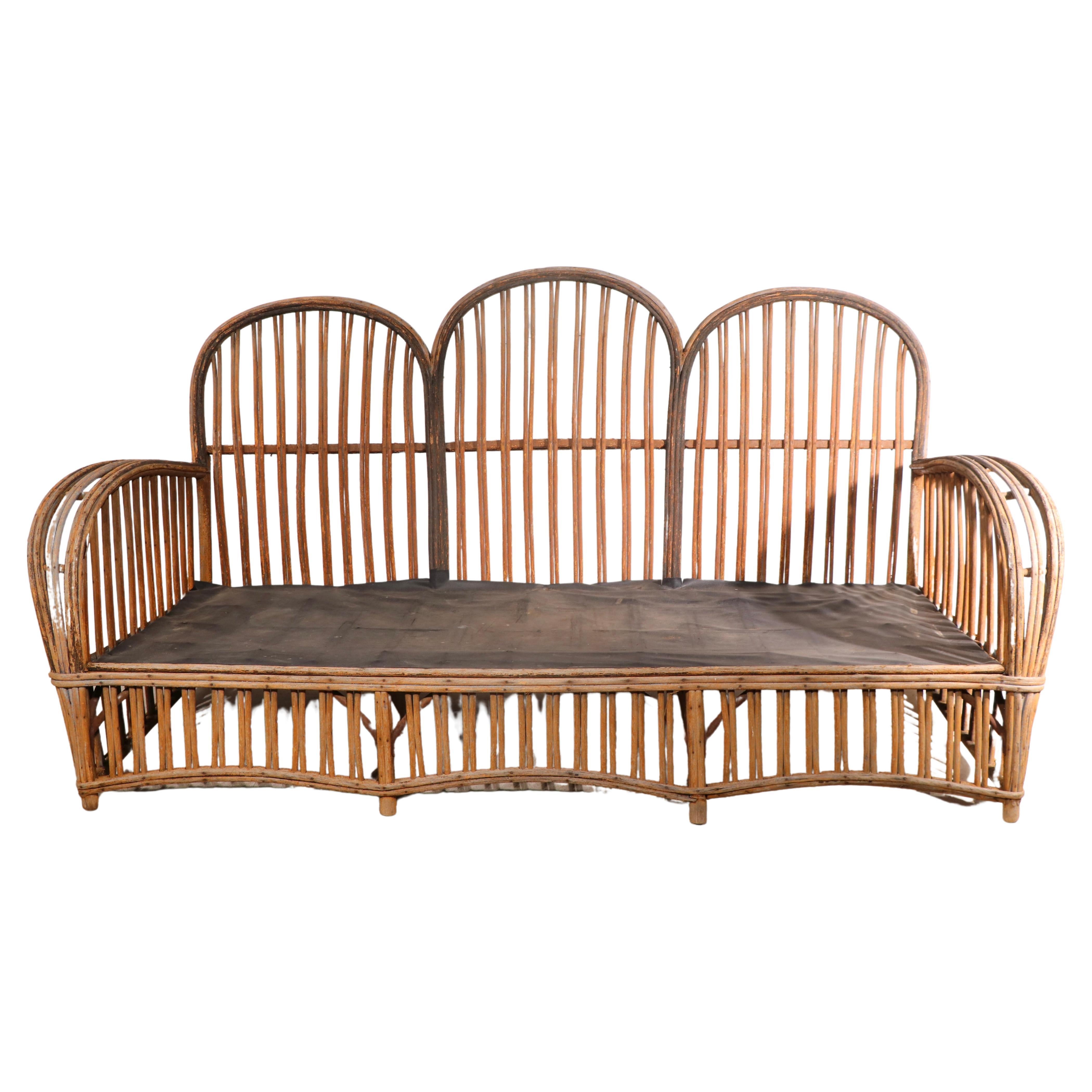 Stylish Art Deco period sofa, constructed of split reed, stick wicker. This example is structurally sound and sturdy, the finish shows significant weathering, there is some minor loss to trim wrapping, the cushions are not included. 
Total H 36 -