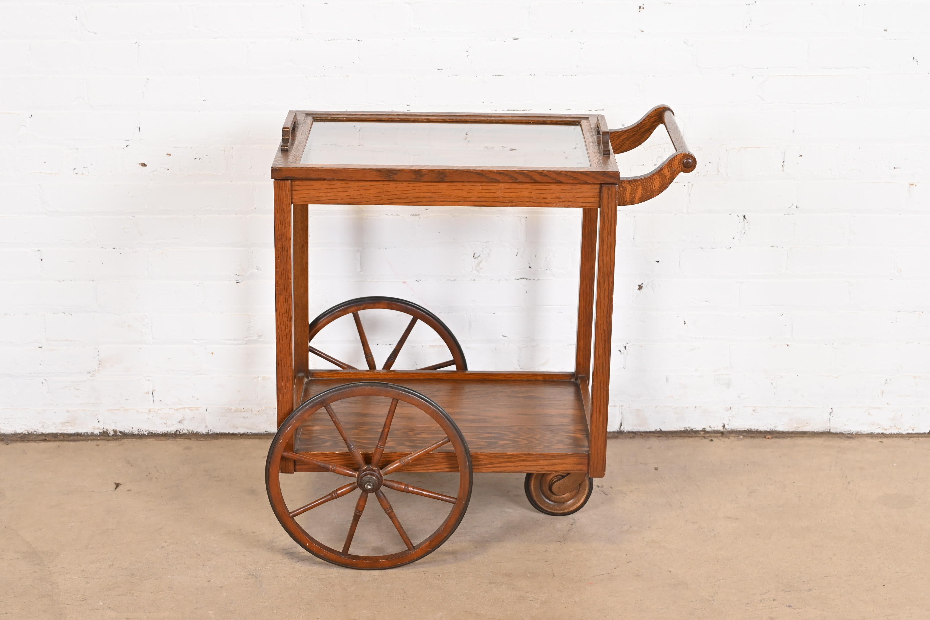 An exceptional Arts & Crafts or Mission tea trolley or bar cart server

By Stickley Brothers

USA, Circa 1900

Oak, with removable glass top serving tray.

Measures: 28.5